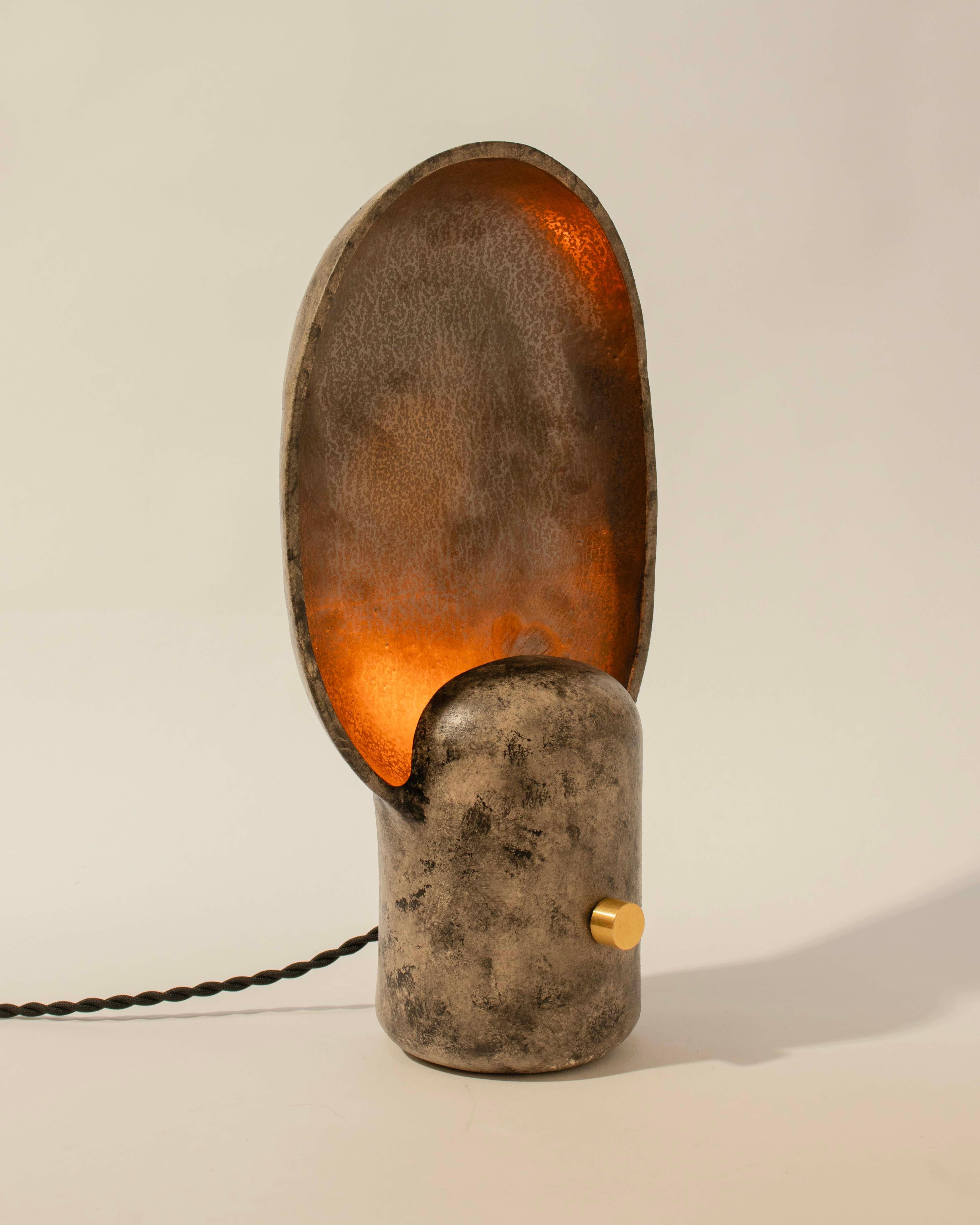 La lampe Paddle est une petite lampe de table d'inspiration brutaliste, parfaite pour un éclairage de chevet ou d'appoint dans les grands espaces, créée par Streicher Goods à Brooklyn, NY. 

La lampe présente un sommet en forme de plat qui s'évase
