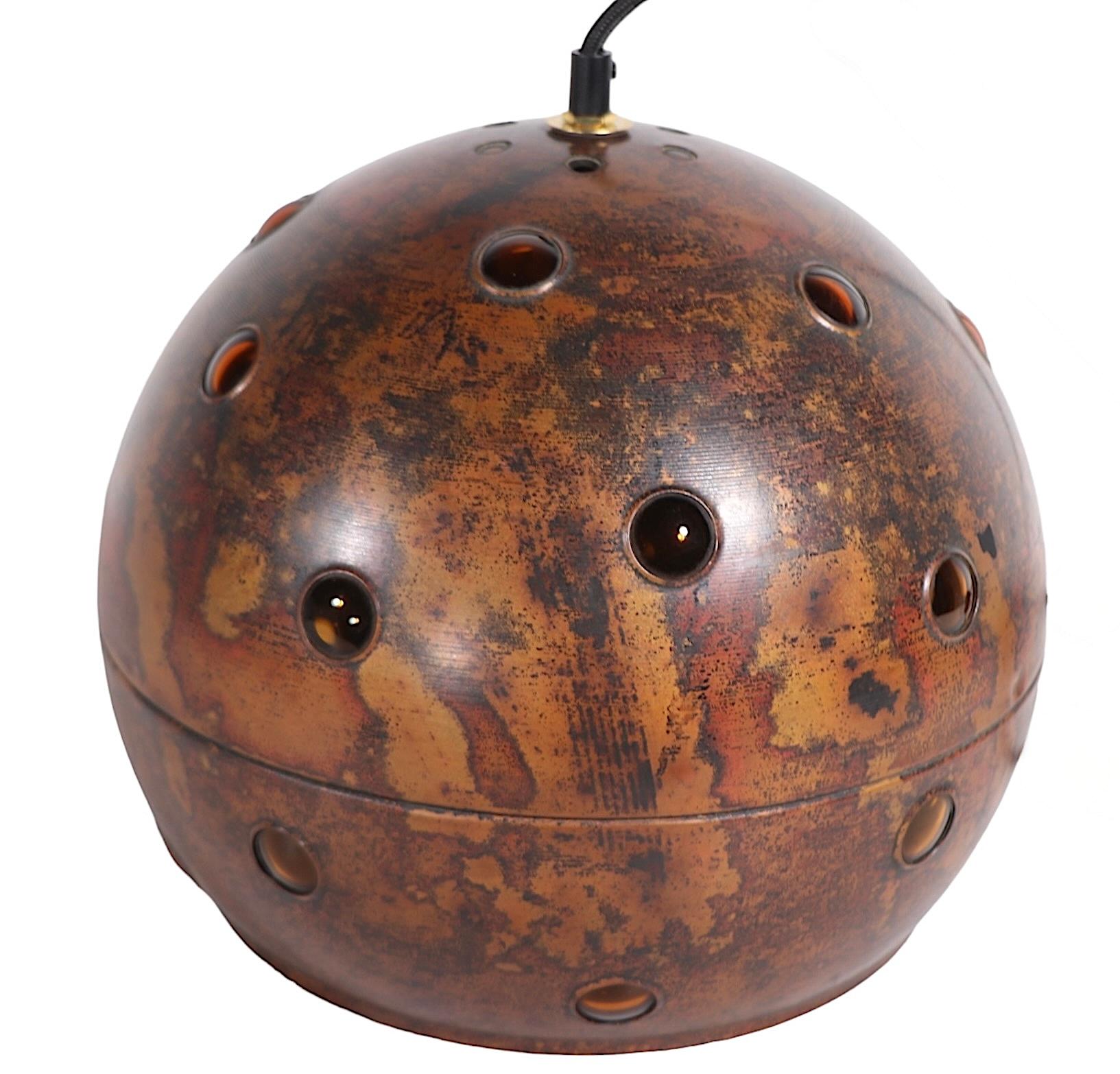 Eccezionale apparecchio a sfera sospeso in stile brutalista del noto designer Nanny Still - McKinney, per  RAAK, circa anni '60. Il lampadario è caratterizzato da un globo di cooperazione con un interno in vetro ambrato, con finestre decorative a