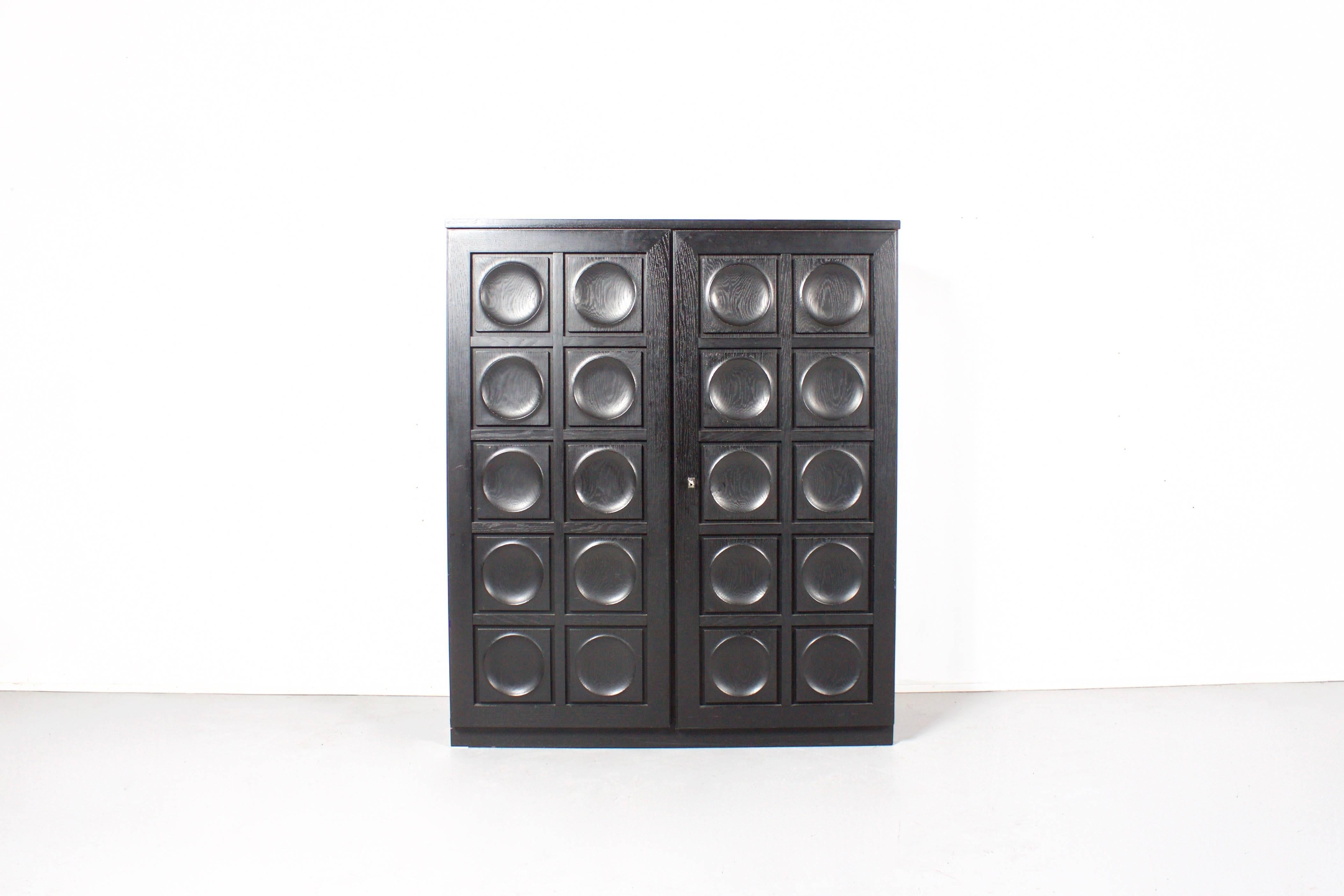 Impressive Belgium Brutalist cabinet in very good condition 

This sideboard has two doors made of massive black stained oak, each with a three-dimensional pattern of circles. 

Behind the doors you can find three shelves and plenty of storage