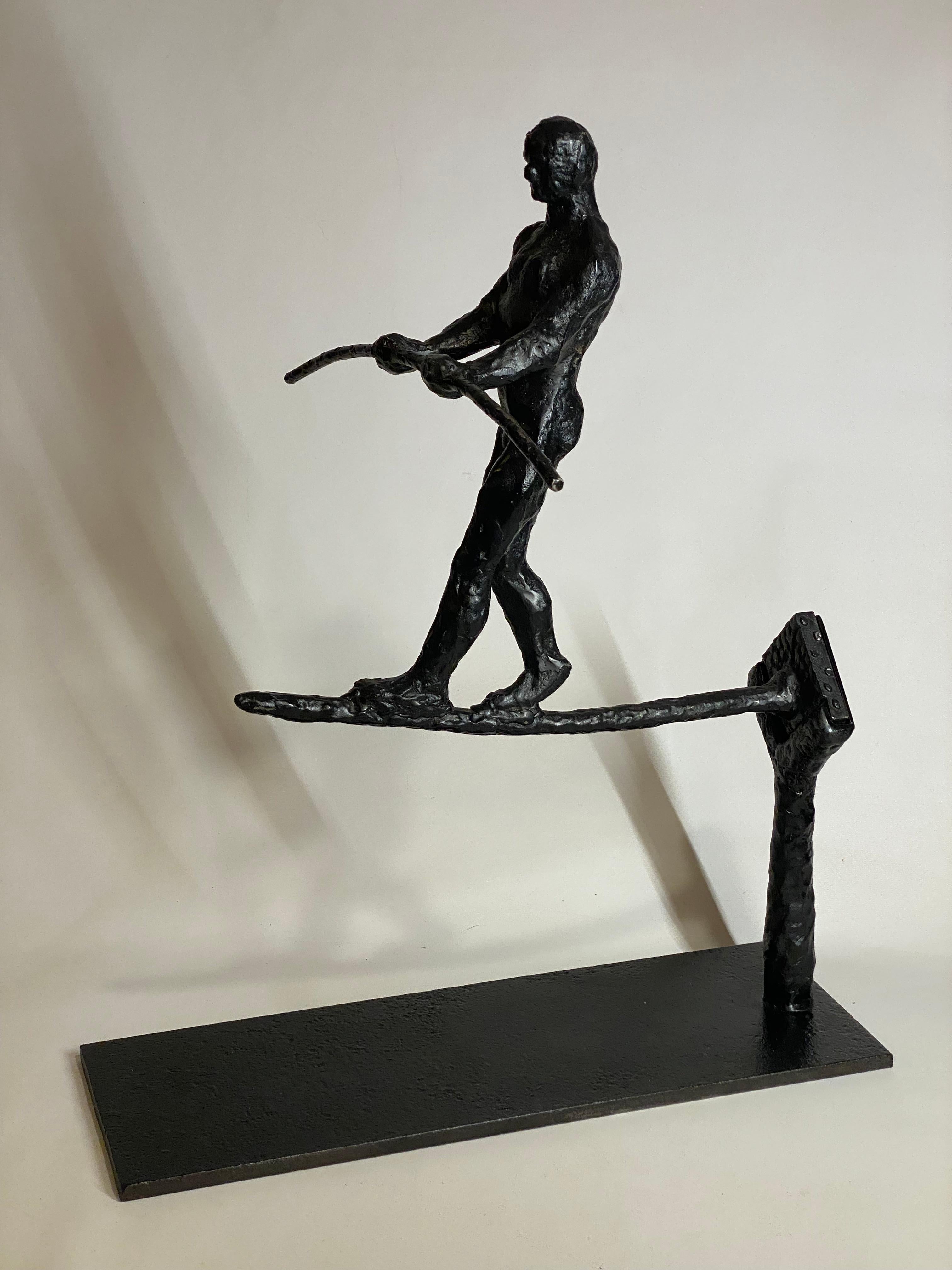 Brutalist period highwire artist in black patinated steel. The aerialist artist comes in two piece with the base and the actual sculpture that fits into the shoe on the base. The artist has rendered the muscular male figure perfectly balanced with
