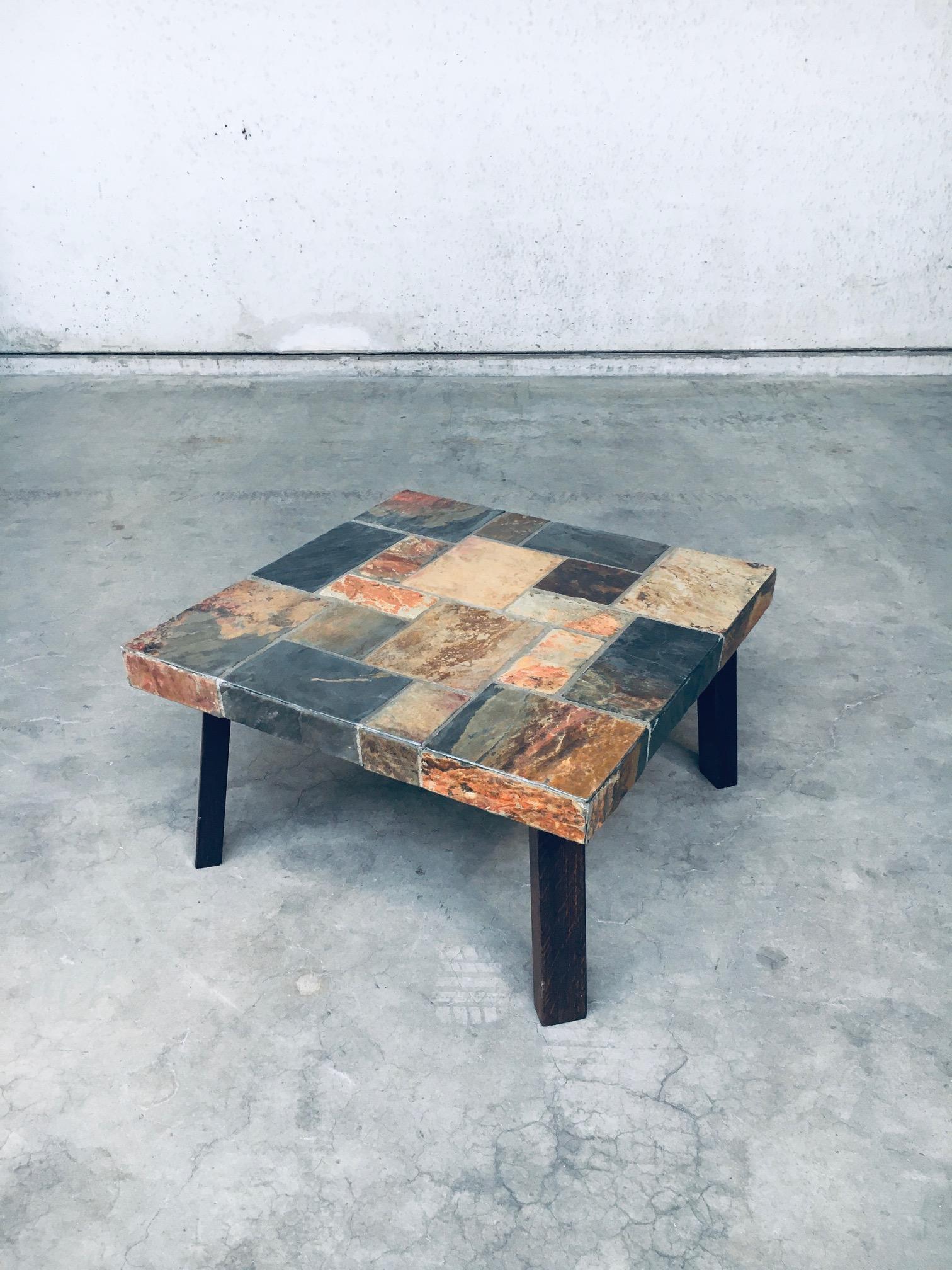 Table basse vintage de style Brutalist avec plateau en pierre d'ardoise. Fabriqué en Belgique, années 1970. Plateau en mosaïque de carreaux d'ardoise sur 4 pieds en bois de chêne. Les ardoises sont de couleurs différentes, ce qui les rend très
