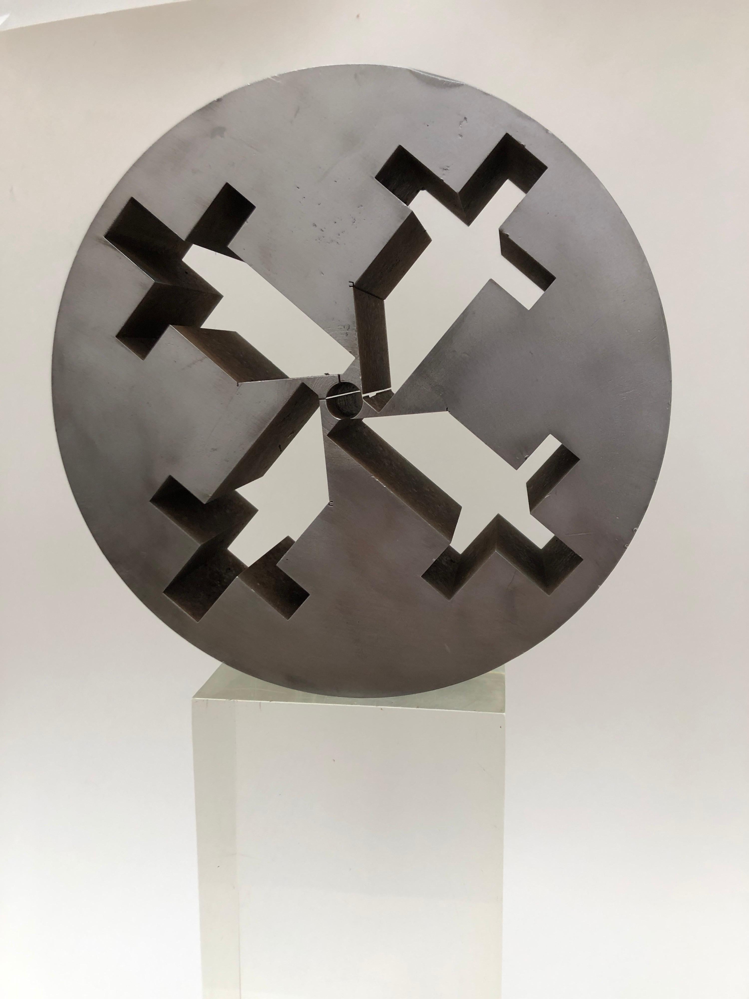 Round heavy steel Brutalist inspired sculptural piece with 4 cross like cut outs. Possibly an old industrial mold. Very graphic piece and can sit with the crosses pointing in any direction. Comes with a vintage solid Lucite base. Metal piece alone