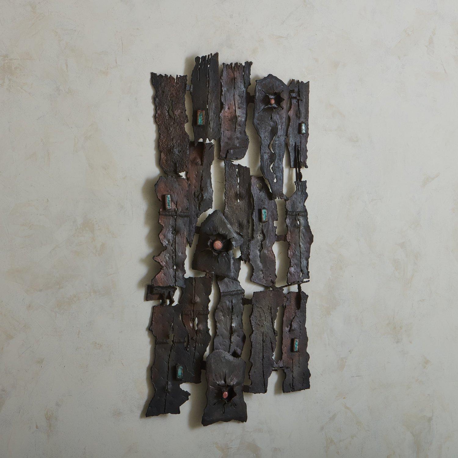 A 1970s French brutalist wall sculpture created with patinated iron. This piece has rich textures and raw edges. It has beautiful inlaid ceramic detailing in pink and blue hues. Unsigned. Sourced in France, 1970s.