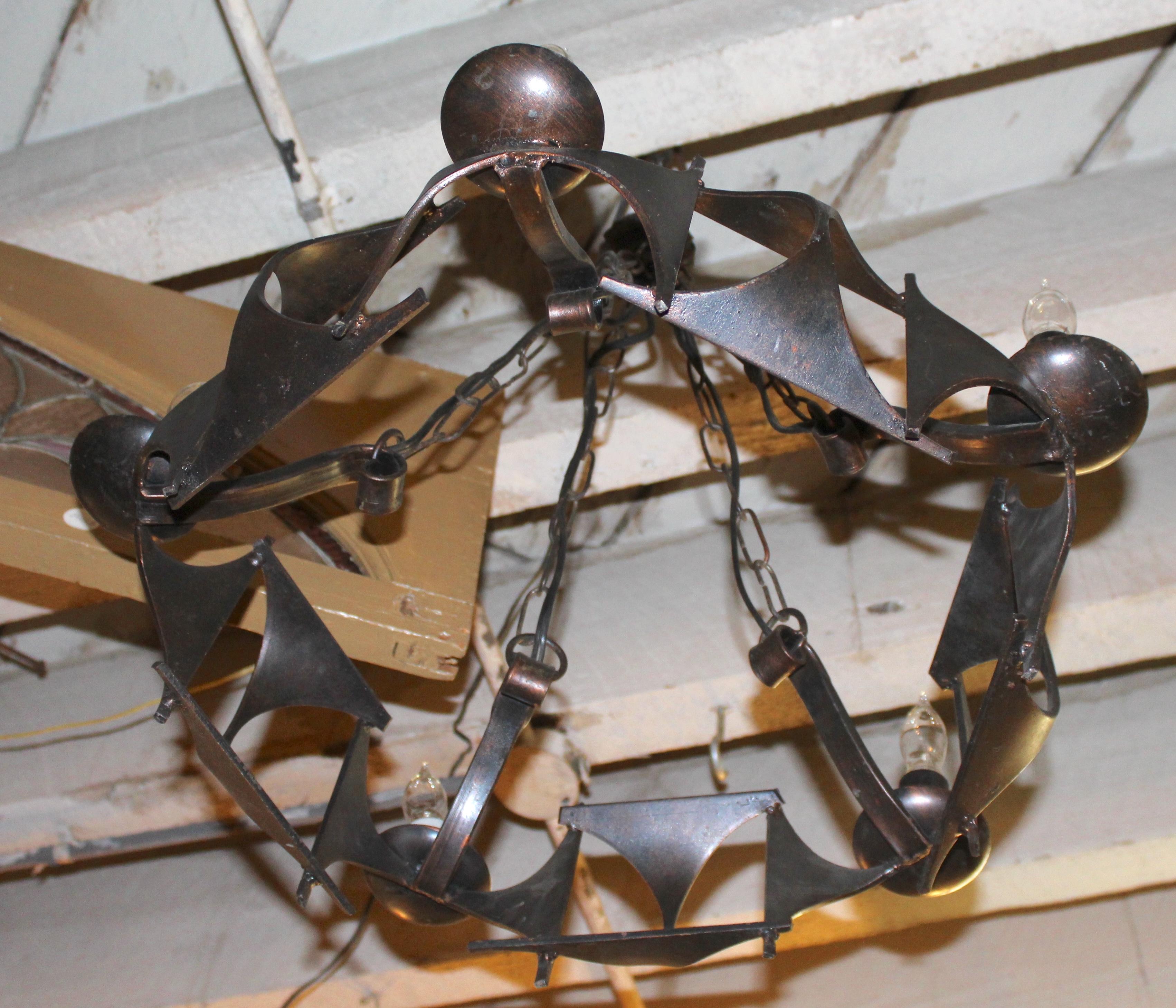 Araña colgante hecha con piezas de hierro soldado que forman un diseño de estilo gótico y brutalista. Cinco brazos para bombillas de casquillo mediano.
Por favor, confirme la ubicación NY o NJ