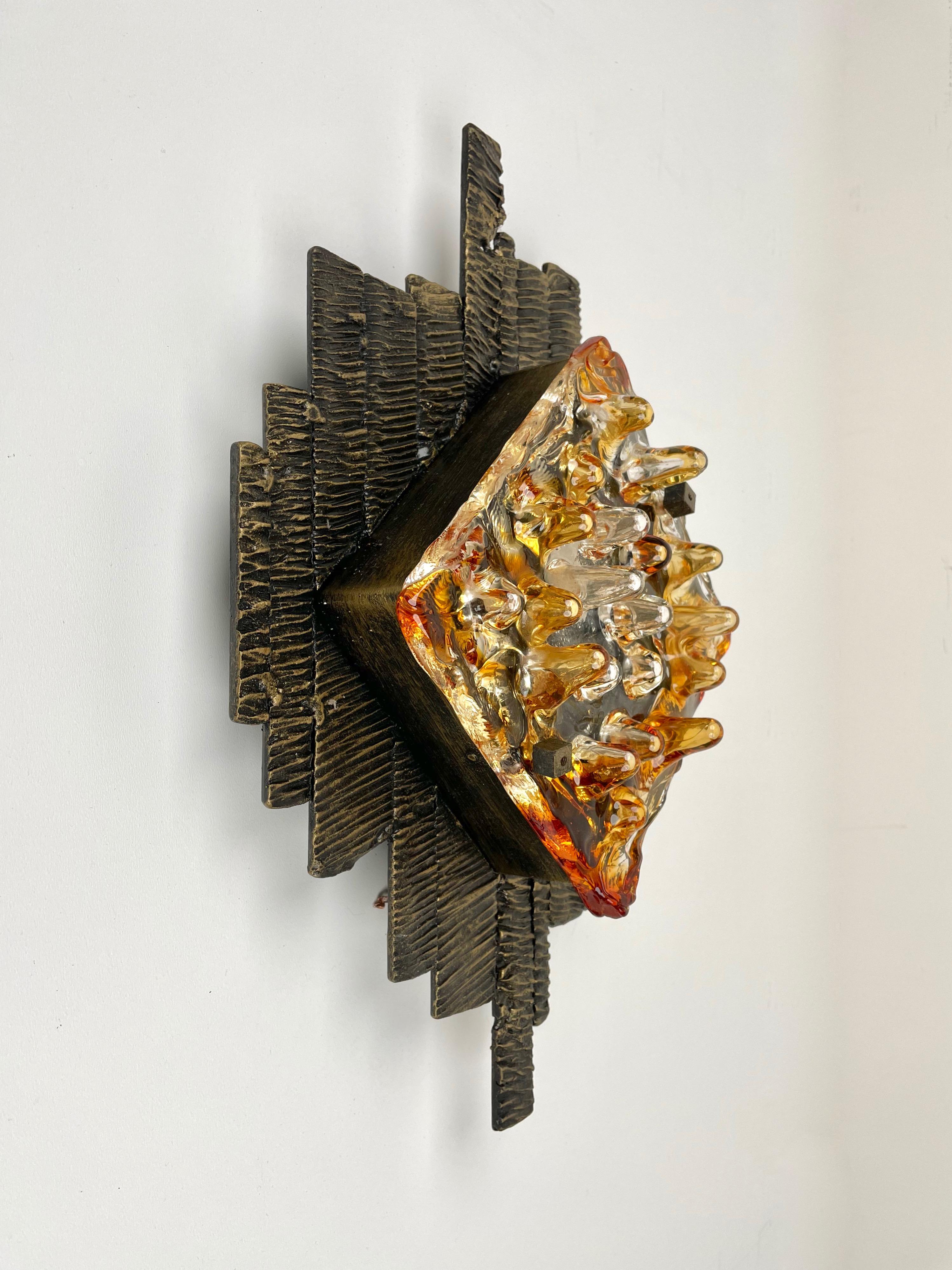Brutalist Mid-Century Modern vintage sconce applique by Tom Ahlström and Hans Ehrlich manufactured by A & E Lights Sweden in the 1970s. 

The sconce has a heavy dark iron structure and a two-tone (transparent and amber) texture in its unique