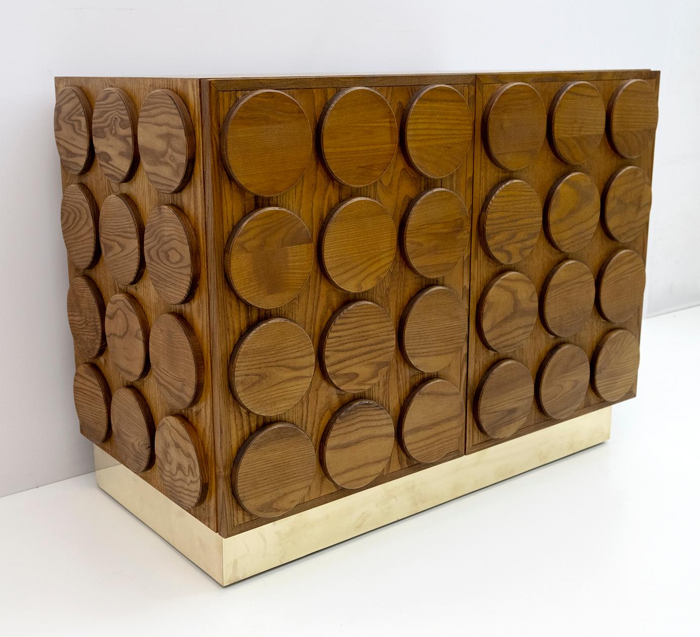 Brutalist dry bar cabinet in chestnut wood. With geometric and harmonious lines, the piece of furniture is also embellished by the brass band below.