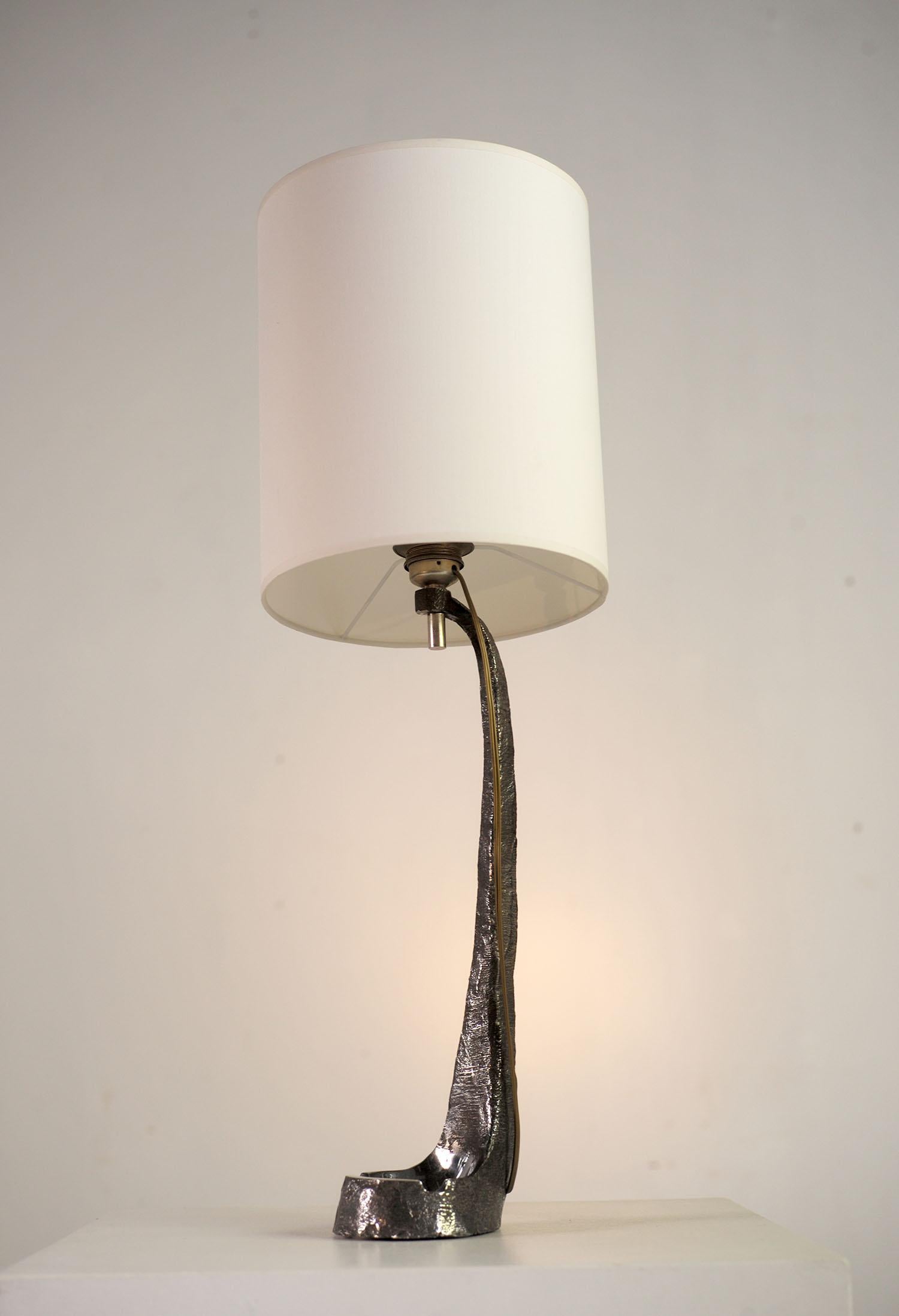 Grande lampada brutalista in solido acciaio inossidabile, Francia 1970. Il blocco di metallo è stato lavorato in massa, lucidato a specchio da un lato e grezzo dall'altro. Una ciotola/posacenere forma la base. Questa lampada scultorea è un pezzo