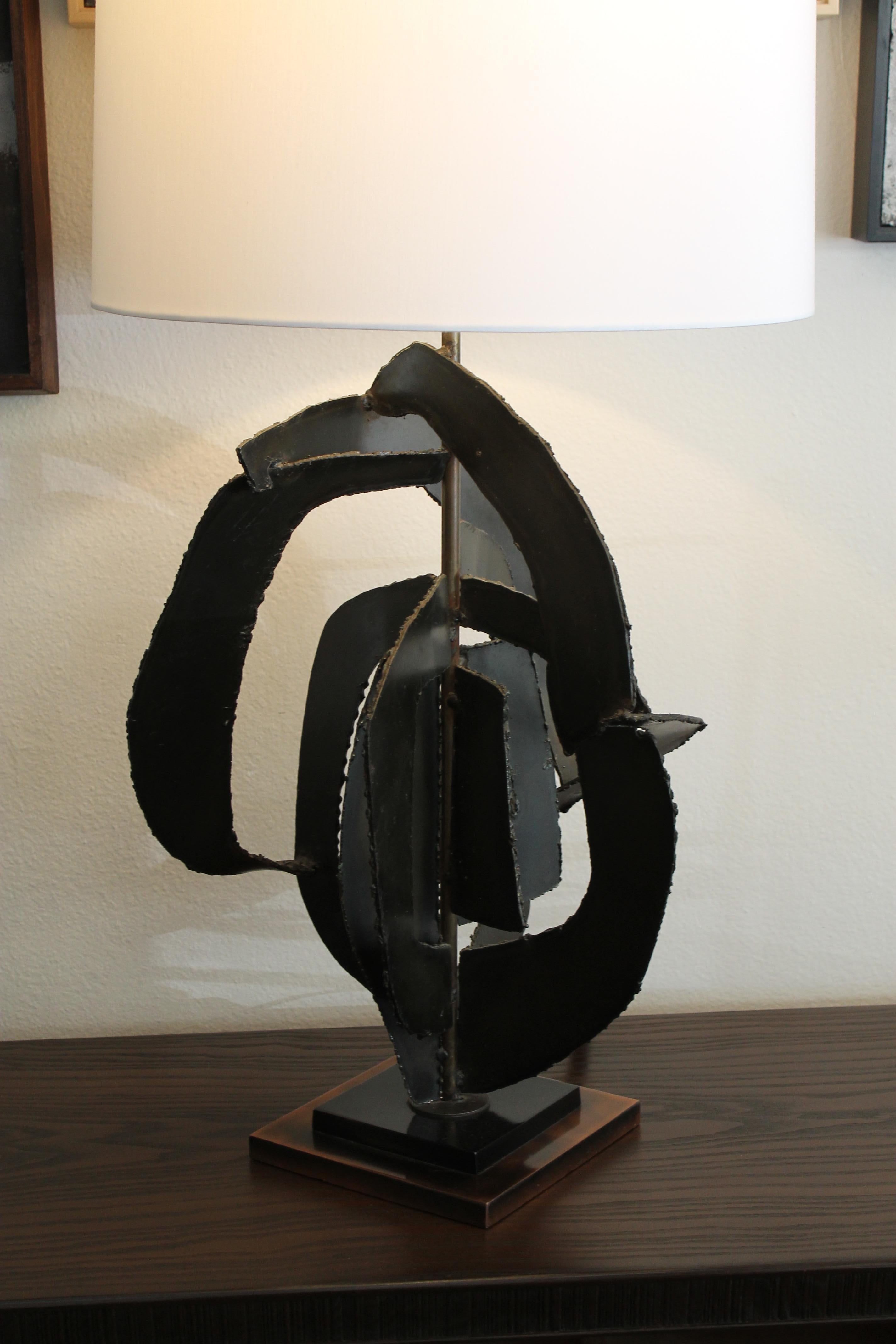 This Brutalist-style lamp was designed by Richard Barr for the Laurel Lamp Company, Newark, N.J. This lamp was one of Barr’s “Studio Collection”. Lamp consists of torch-cut metal on a bronze square base. Lamp is 38.5