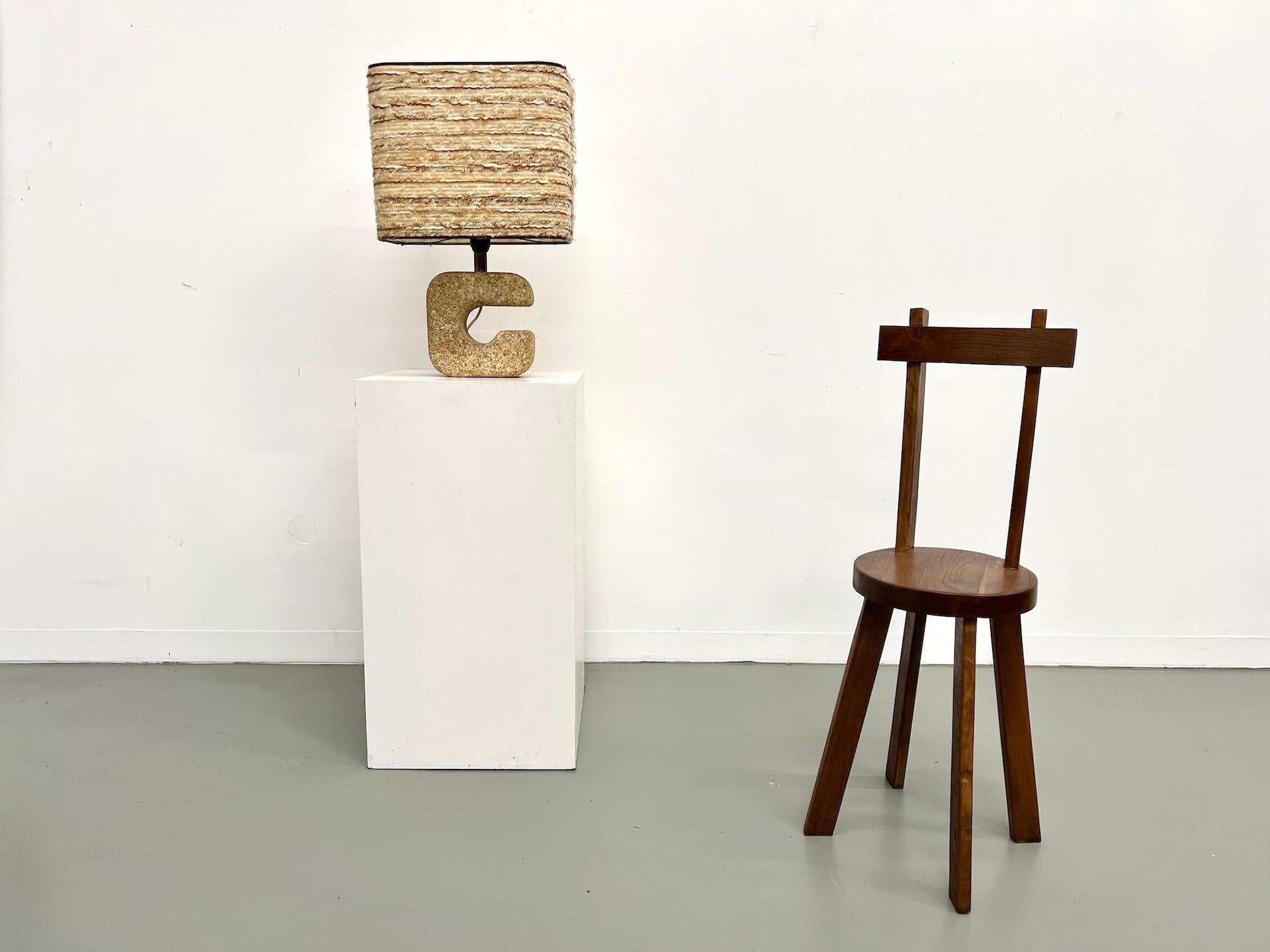 Maison Lecan presenta esta impresionante lámpara de sobremesa de los años 70, que combina líneas escultóricas con una elegancia cruda.

La base, de piedra reconstituida, presenta una silueta orgánica y gráfica que recuerda a Michel Tormos y al
