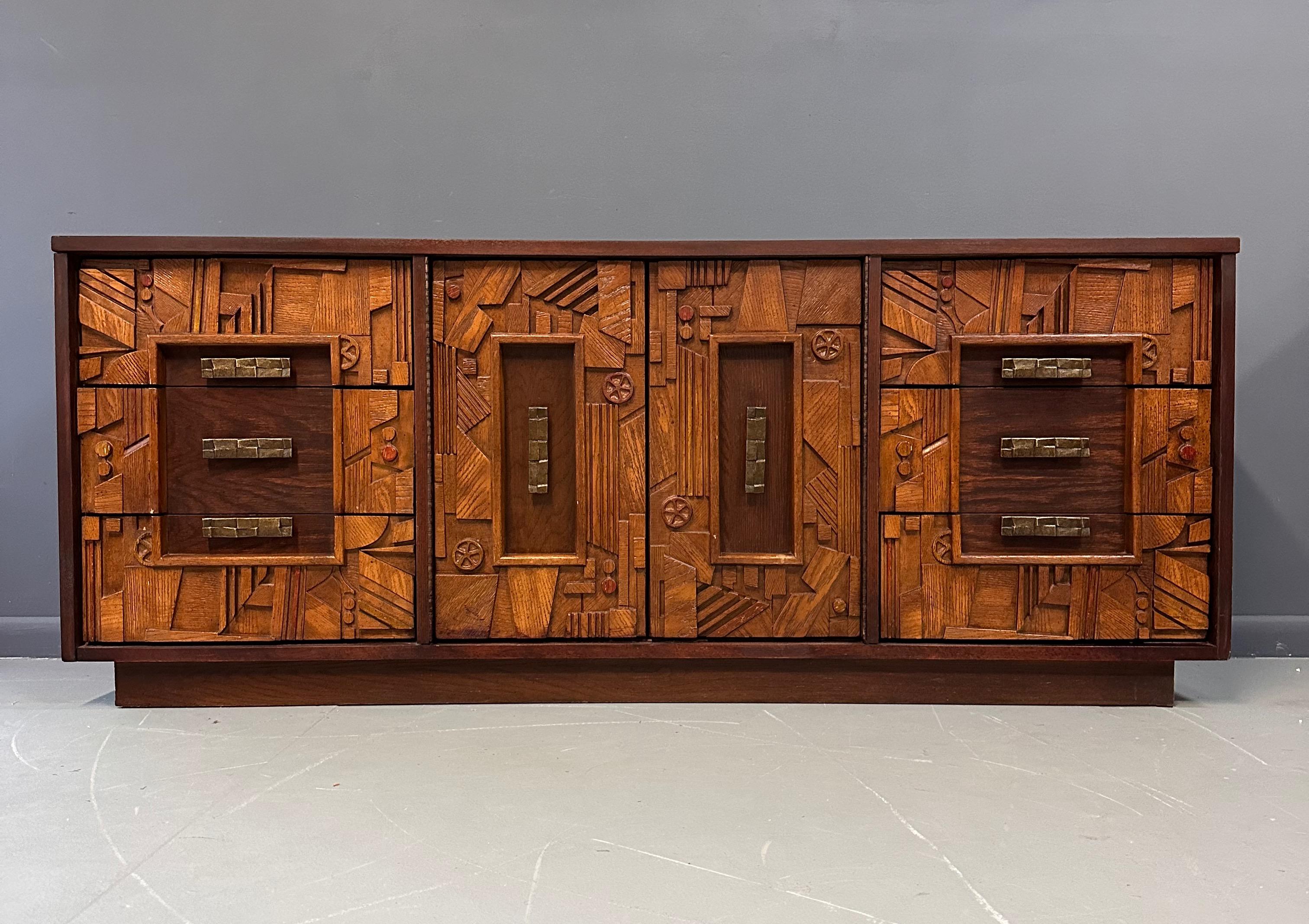 A stand out Paul Evans style oak and composite Brutalist triple dresser with an intricately laid, highly textured pattern adorning the front facade. The rough hewn forms exemplify the Brutalist aesthetic. This dresser contains ample storage with a