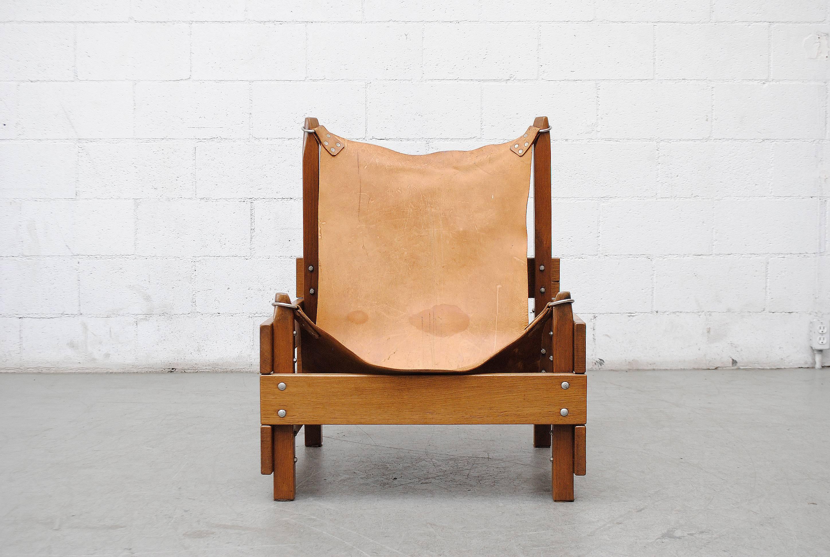 Super cool midcentury Brutalist, Safari inspired lounge chair. Natural leather sling seat with metal loops. Lightly refinished wood frame. Wear consistent with age and use.