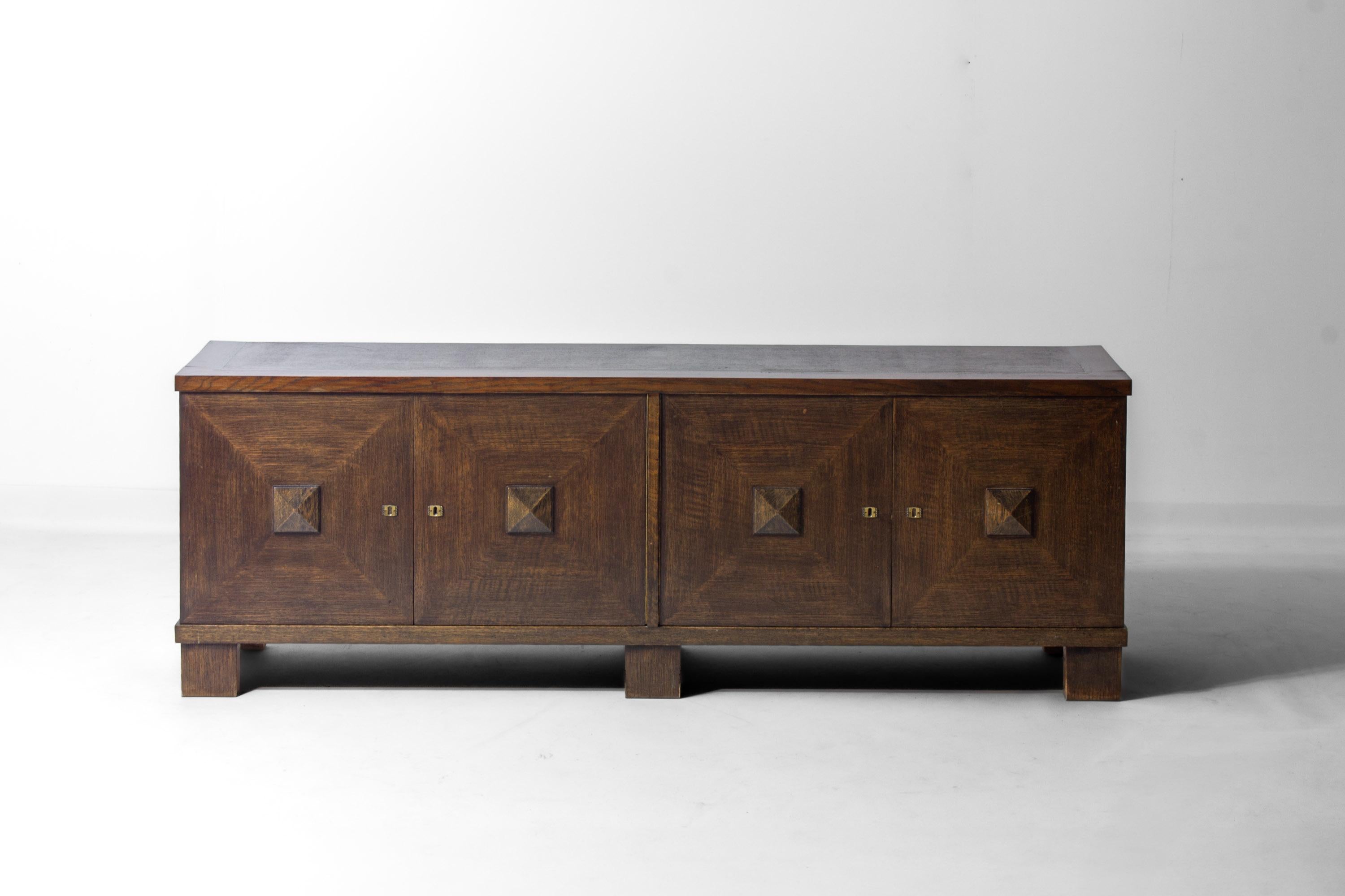 Lowboard aus massiver Eiche mit dunkel gebeizter Oberfläche, hergestellt in den 1970er Jahren. Das Stück verfügt über vier Fronttüren mit geometrischen Reliefs, in deren Mitte sich jeweils ein pyramidenförmiges Motiv befindet.
