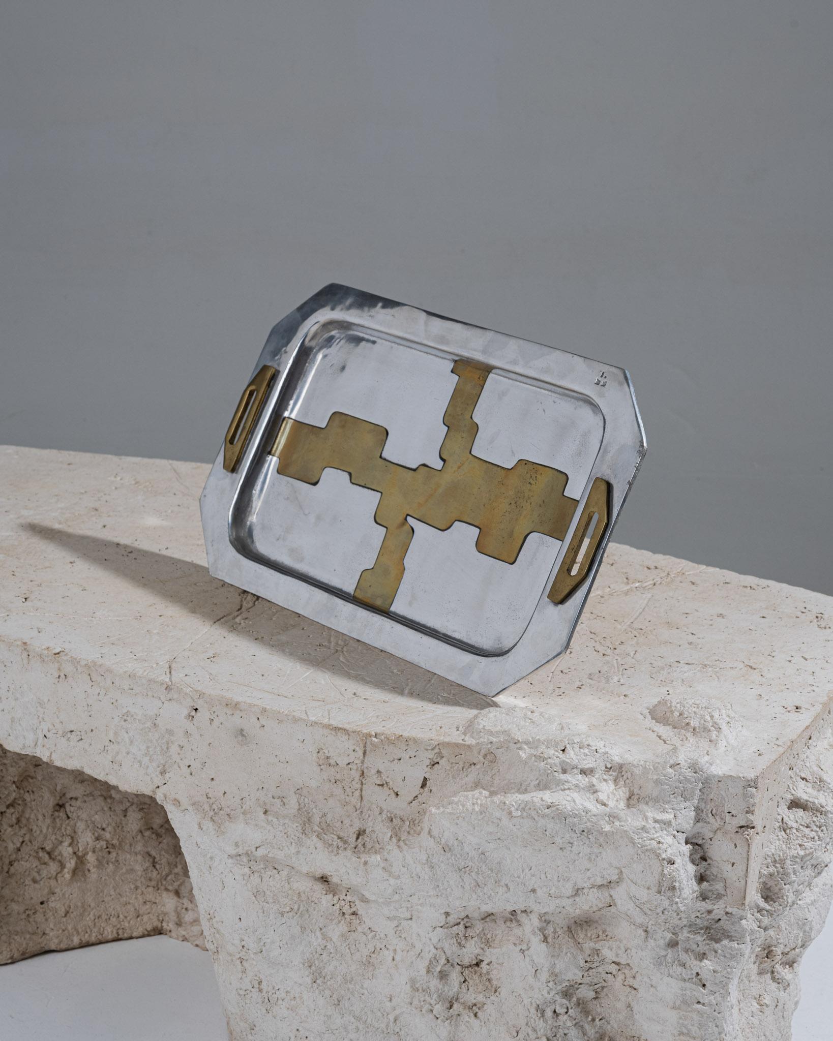 Plateau en aluminium et laiton aux bords biseautés, orné de formes libres et de deux poignées en laiton. Œuvre espagnole de David Marshall, emblématique du design brutaliste des années 1970. Le dessous est doublé de cuir beige pour protéger les