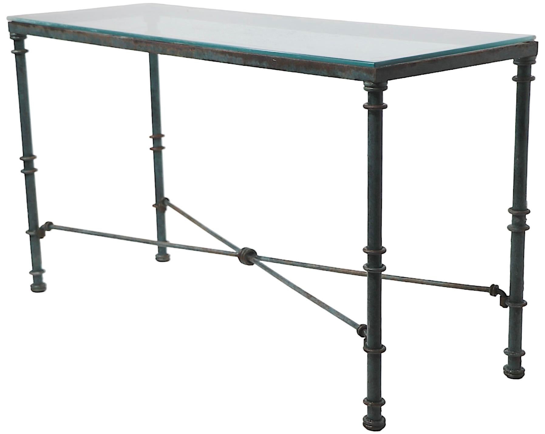 Schicker brutalistischer, romanischer Konsolentisch aus Eisen und Glas nach Giacometti. Der Tisch besteht aus einem Metallgestell mit Rohrbeinen, dekorativen Metallringen und einer X-förmigen Streckbank. Die Platte ist aus gehärtetem Glas.
 Dieses