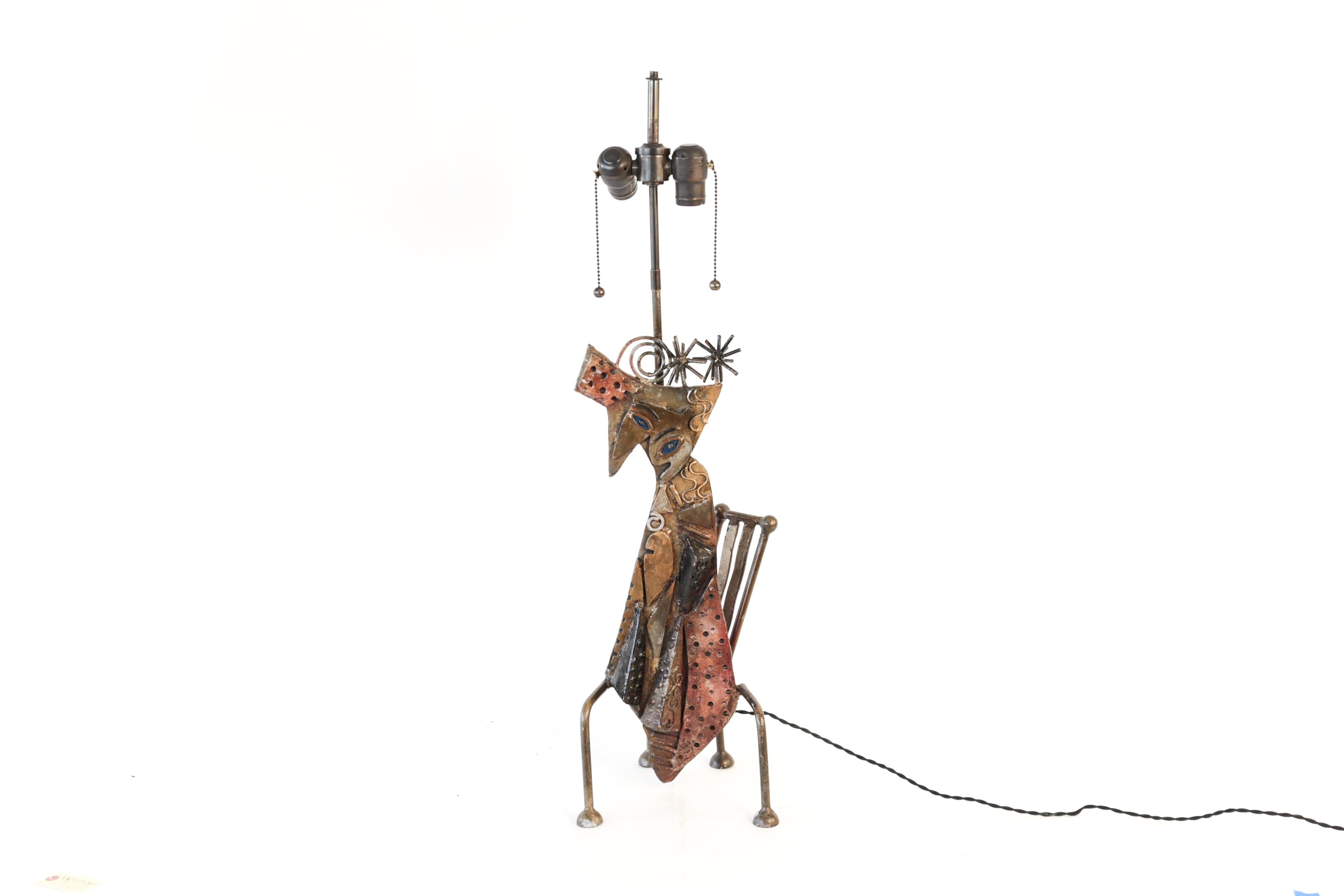 This whimsical handcrafted table lamp depicts a cat on a chair. When lit, the light plays over the textured metal and casts interesting shadows on the wall. With its new sockets and recent rewiring, this lamp is ready to be the newest addition to