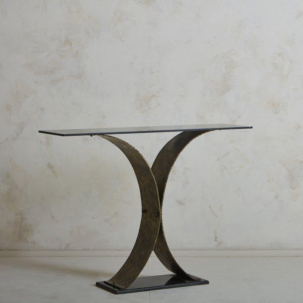 A 1970s hammered steel console table with a patinated finish and a fantastic smoked glass table top. Sourced in Europe, this was most likely made by a metalsmith and commissioned as a one of a kind piece for a decorator. This table has fantastic