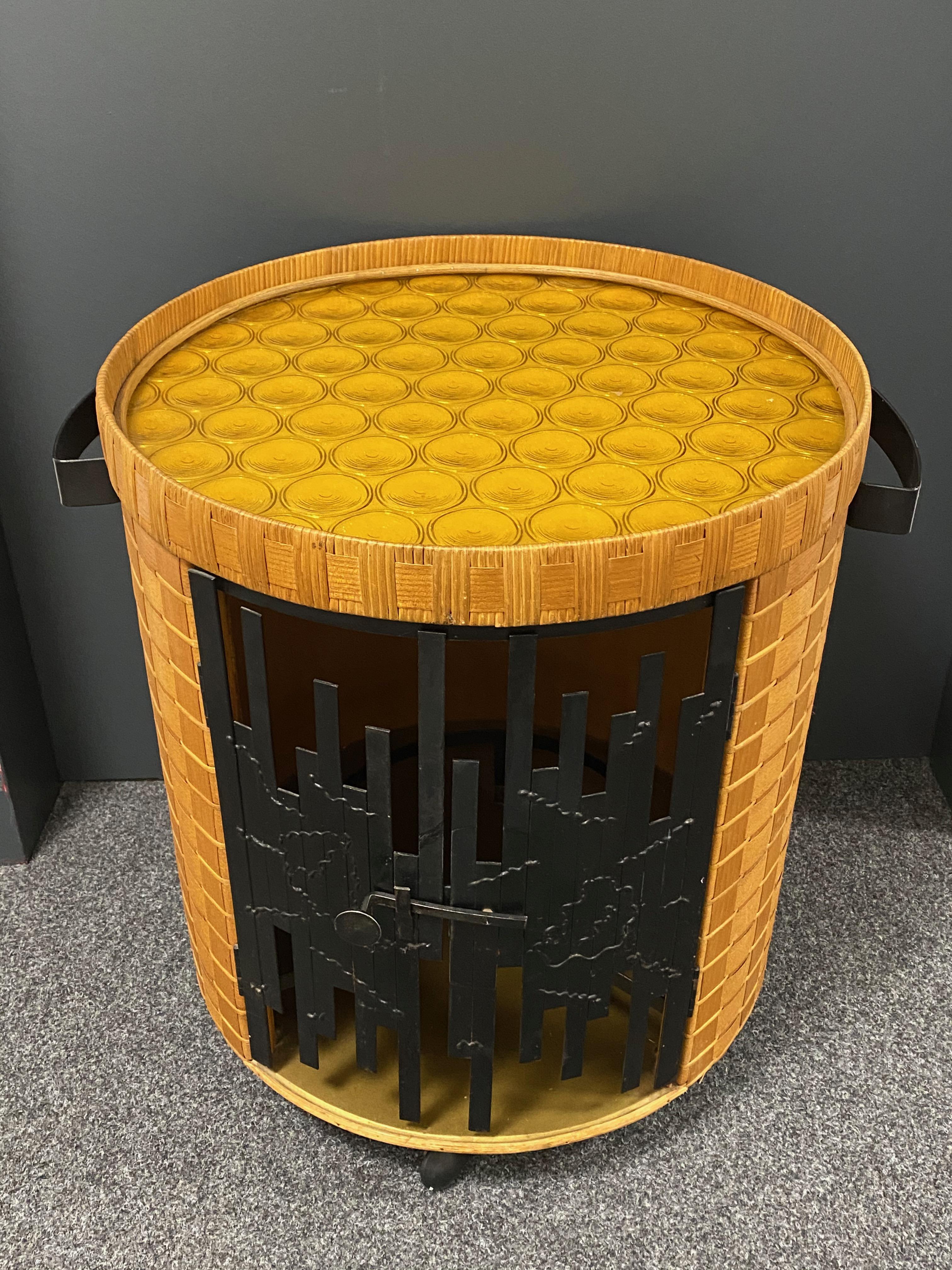 Chariot de bar en forme de tonneau du milieu du 20e siècle, construit en rotin tressé à la main et agrémenté de bois. La porte est en métal et le couvercle est en verre. Une belle addition à votre maison, votre patio ou votre jardin. Il est en état