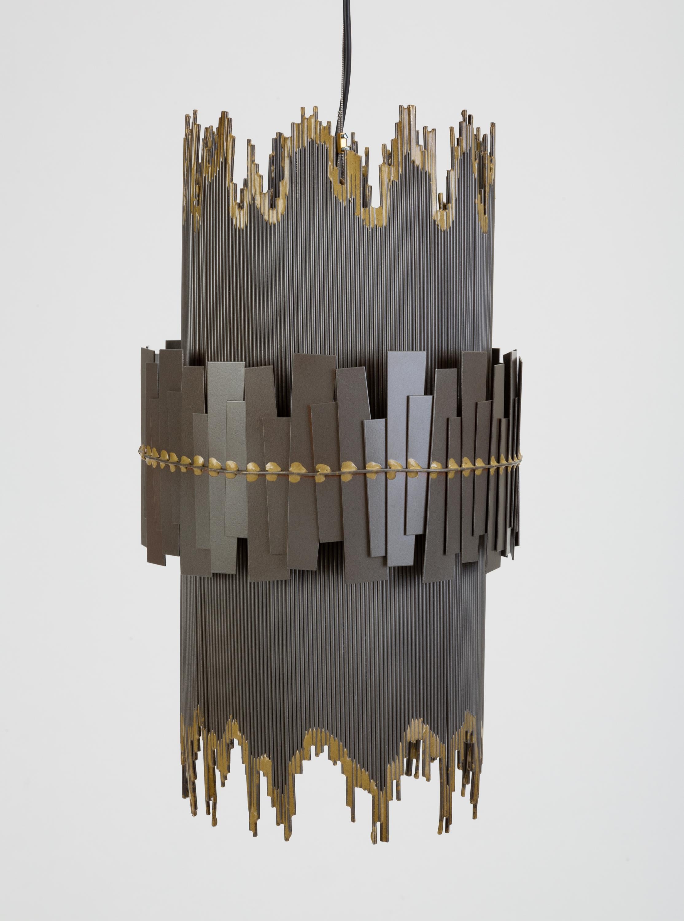 A brutalist metal pendant lamp with a cylindrical shape and irregular edges. The main shape of the fixture has a striated frame with contrasting edges; a slightly wider ring of irregularly welded metal pieces wraps the central circumference of the