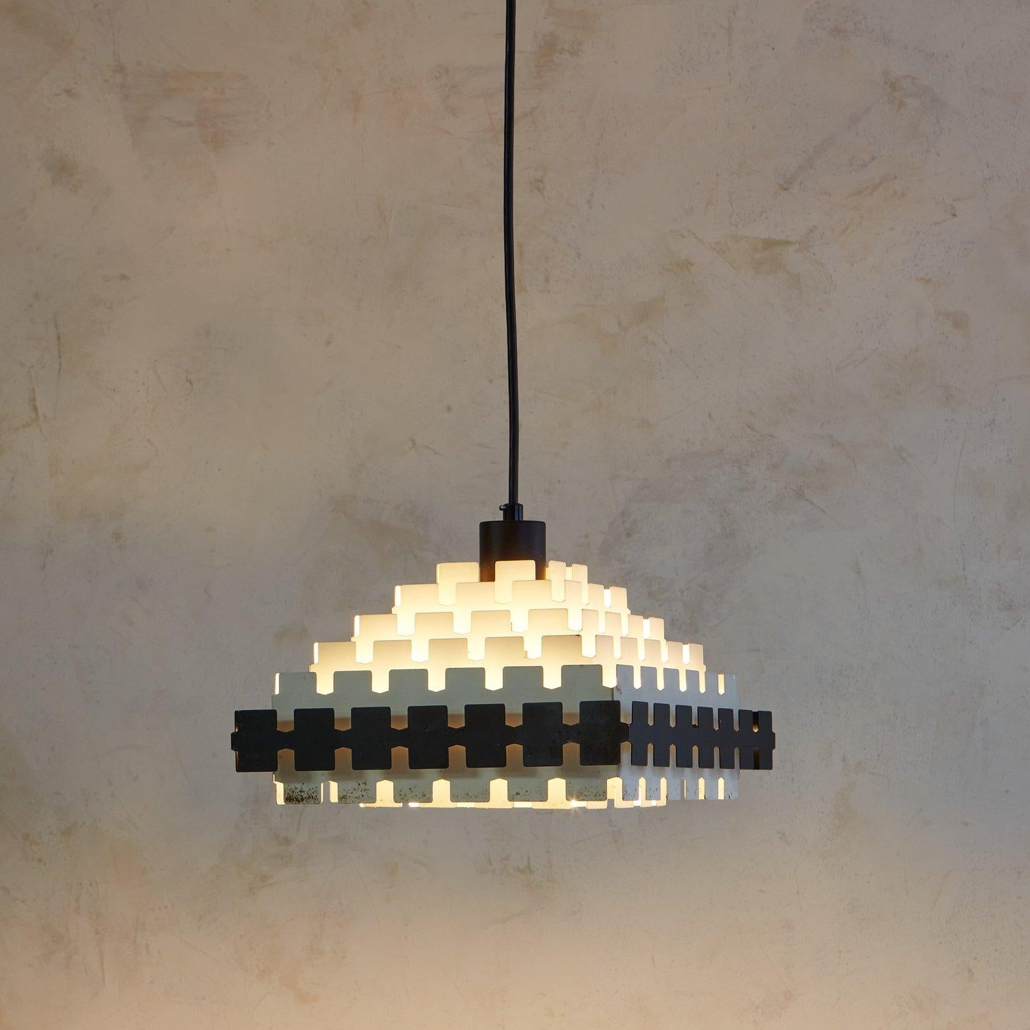 A gorgeous 1960s brutalist pendant light attributed to Doria Lichtenwerken. This pendant was constructed with metal and features seven square tiers with geometric cutout details. One of the tiers is painted black, creating a beautiful color
