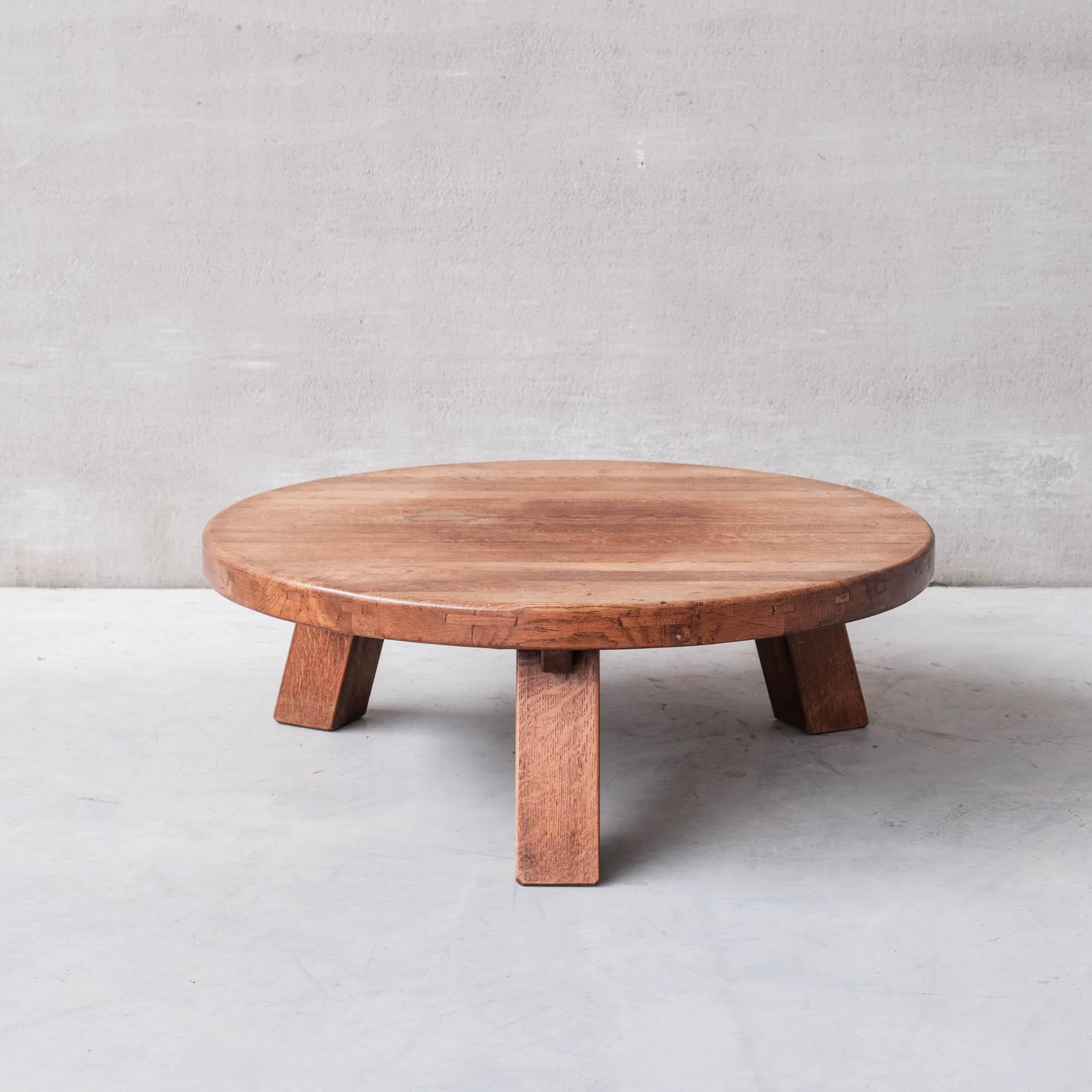 A large oak brutalist style coffee table. 

France, c1970s. 

Thick chunky top raised over tripod legs. 

Good vintage condition, some scuffs and wear commensurate with age. 

Location: Belgium Gallery. 

Dimensions: 40 H x 119 Diameter in