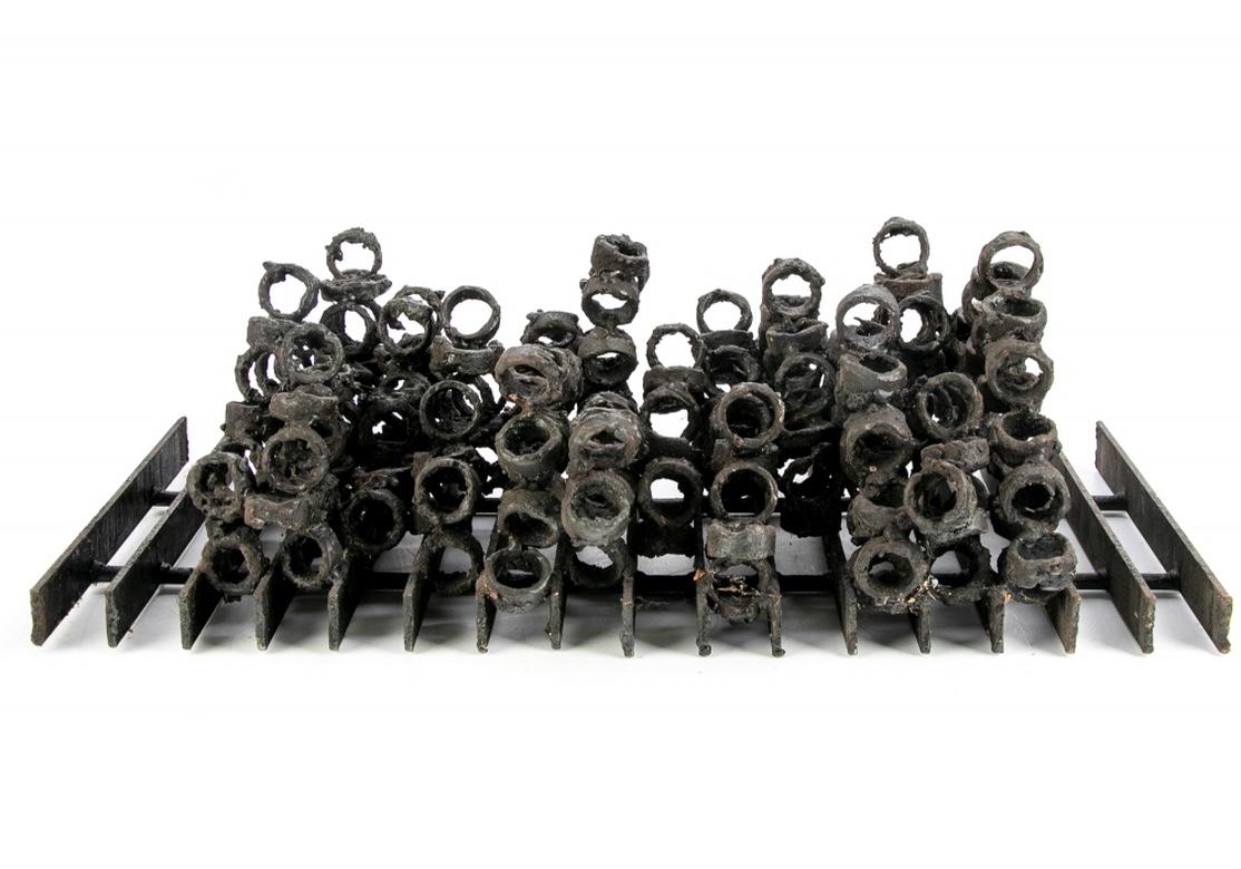 A striking Late 1960s Brutalist midcentury iron sculpture in all very good original condition for the wall or table. Dozens of forged and welded rings in an Abstract form are mounted to an Industrial form grid backing or base. Unsigned.
The