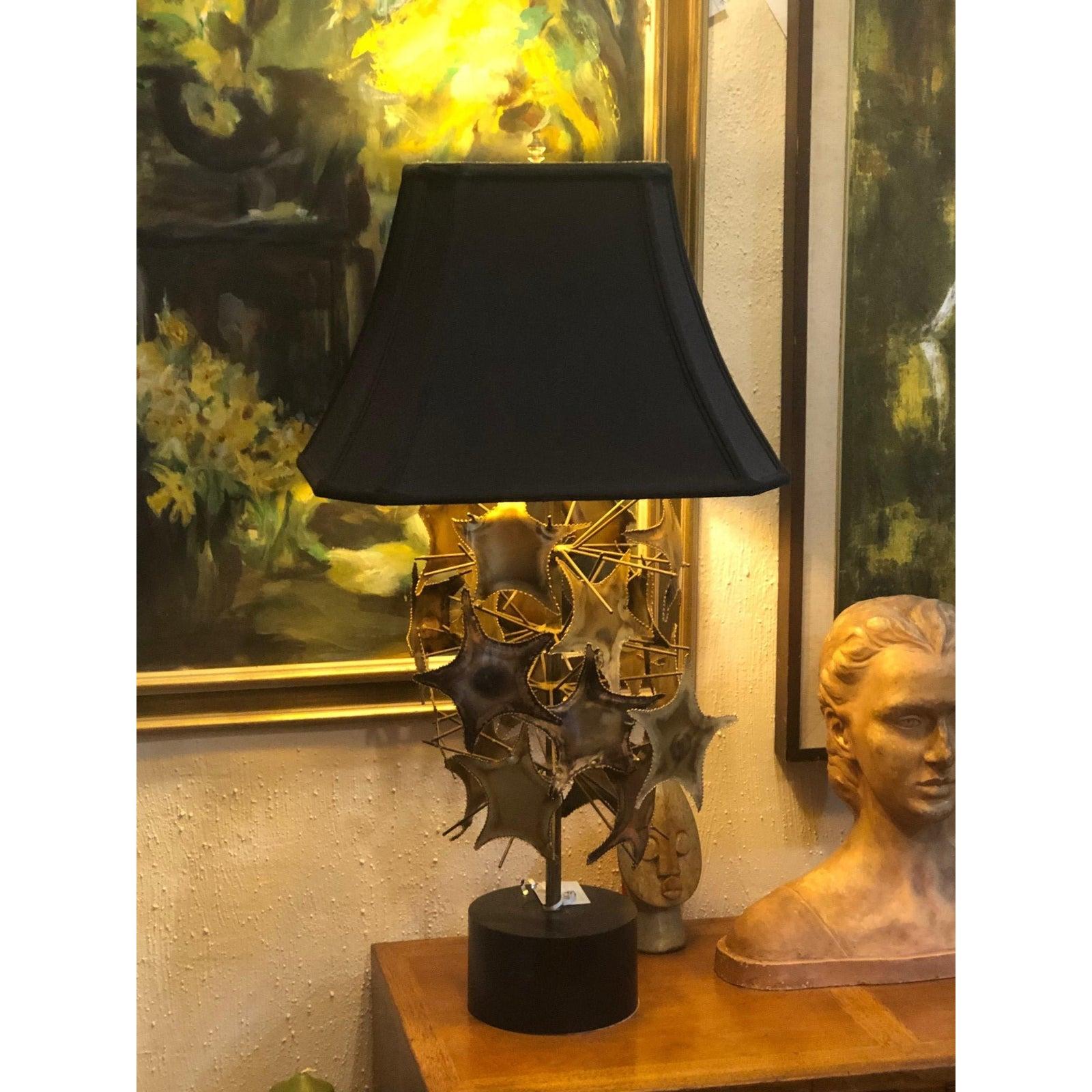 Brutalist Mid-Century lamp in the style of Curtis Jere. Torch cut shapes of stars and branches or starfish and sea urchin-line tentacles. Supported by a round black metal base. Comes with a black silk shade, swithc out for a round black one if