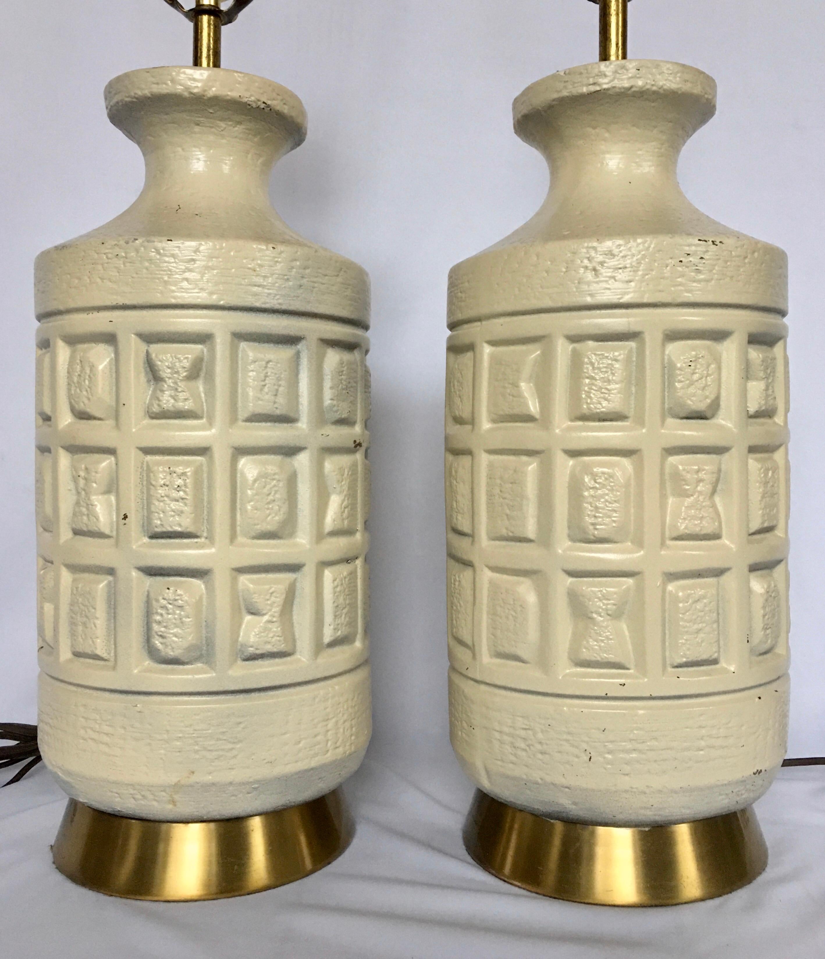 Mid-Century Modern Brutalist pottery table lamps. These cubist form table lamps feature sculptural matte cream pottery bases imprinted with geometric forms mounted on brass bases. 

Measures: Height to Socket 22 inches.
Height to Harp 30 inches.