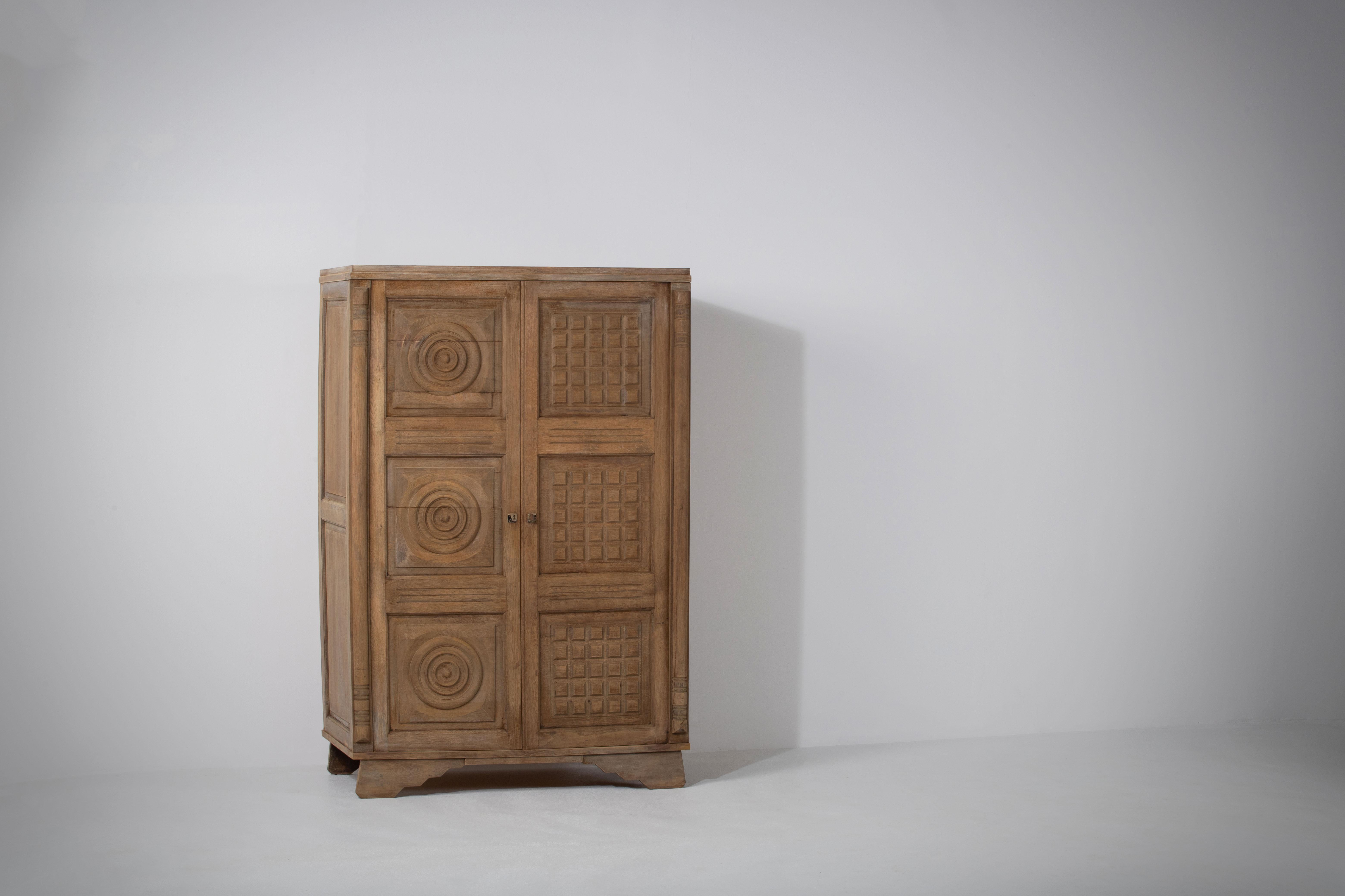 Large oak sculpted wardrobe by Charles Dudouyt in a bleached finish.
France c. 1950.