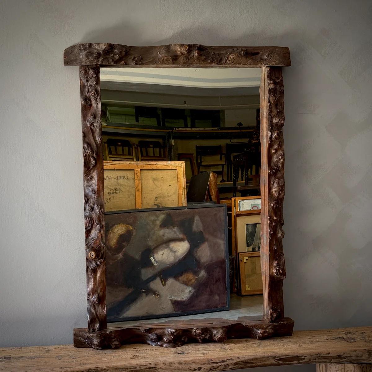 Brutalist mountain-style mirror crafted from natural, heavily textured wood, showcasing its raw and organic form. The rich grain, knots, and imperfections emphasize its rugged aesthetic, embodying the essence of Brutalism while maintaining a warm,