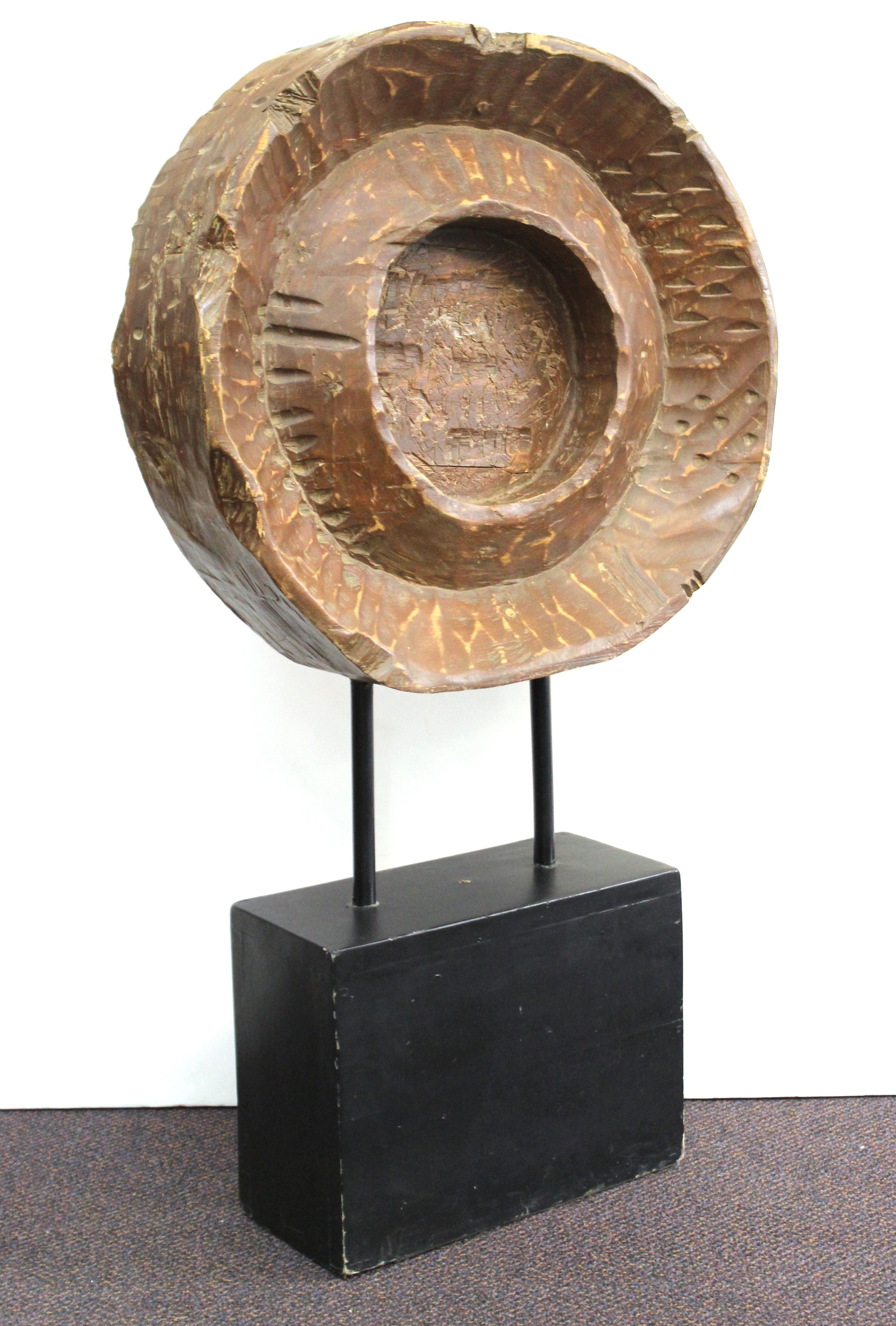 Brutalist modern monumental carved wooden disc or wheel-shape mounted atop an ebonized base. The piece was likely made during the mid-20th century and is unsigned. In great vintage condition with age-appropriate wear and use.