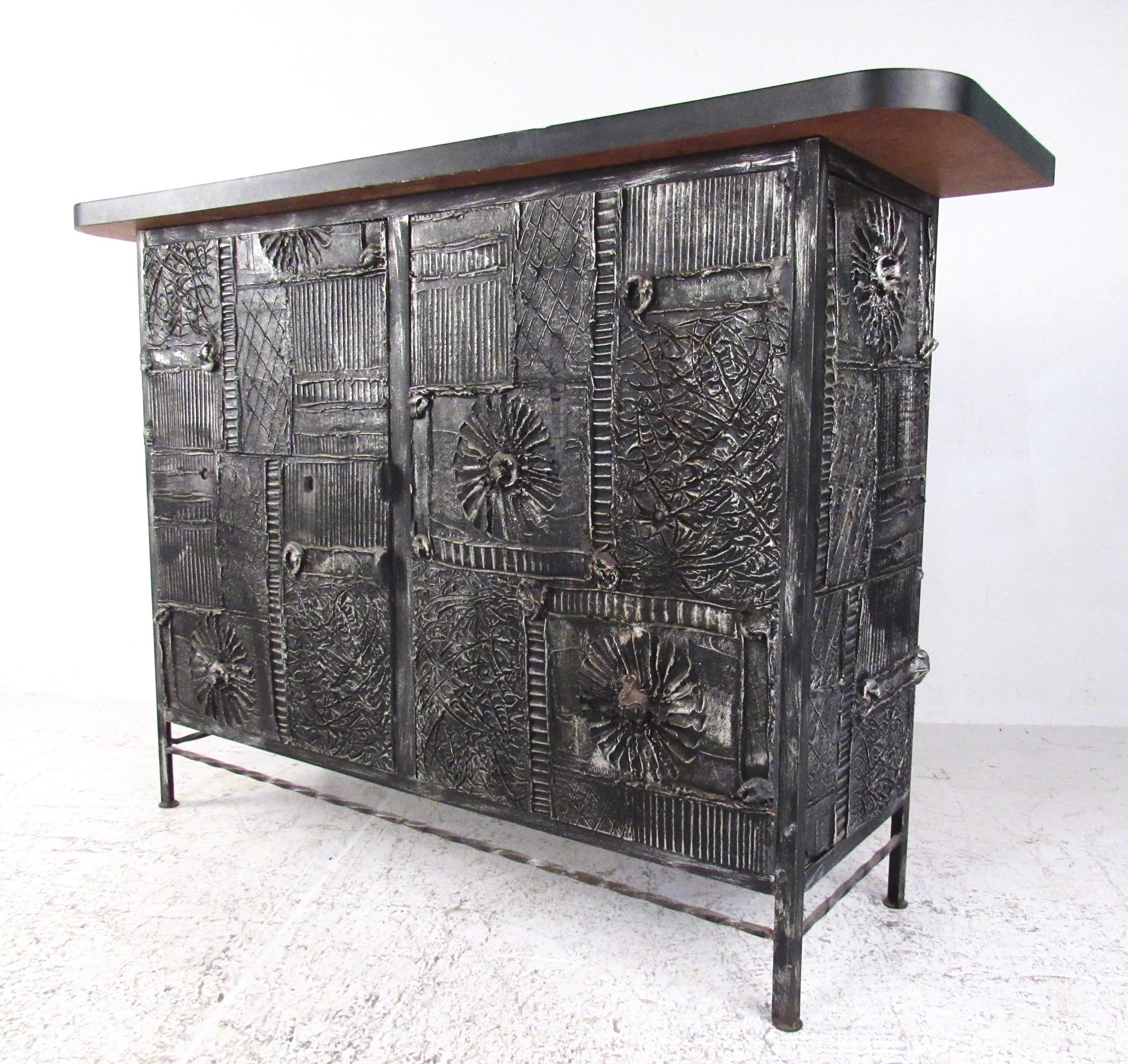 This stylish vintage home bar set includes a striking Brutalist modern dry bar and pair of matching bar stools. The decorative textured finish of this unique bar is similar to the iconic Mid-Century Modern design of Adrian Pearsall, making a