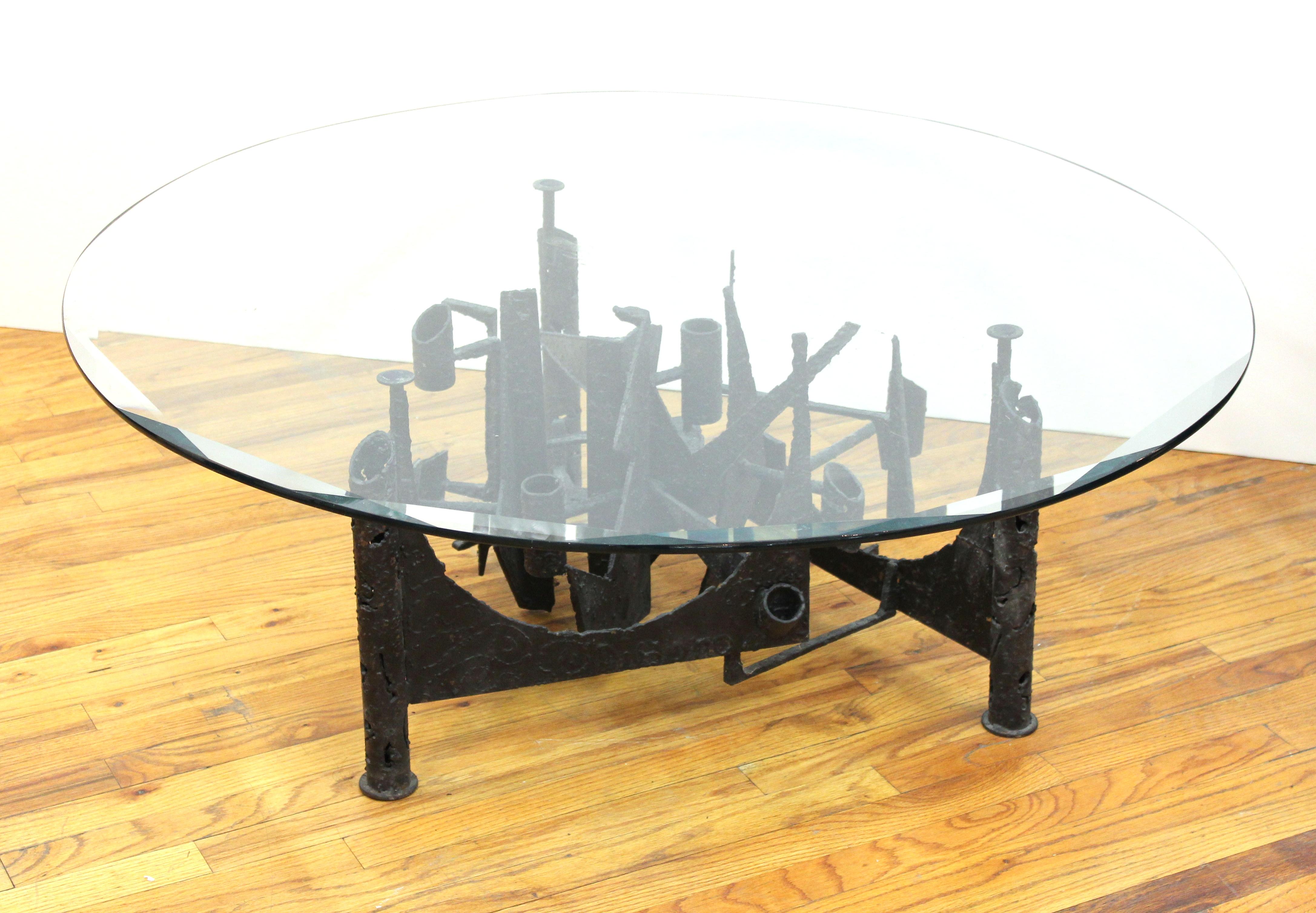 Brutalist modern coffee table or cocktail table with welded abstract metal base and beveled round glass top, in the style of Paul Evans. In great vintage condition with age-appropriate wear and use.