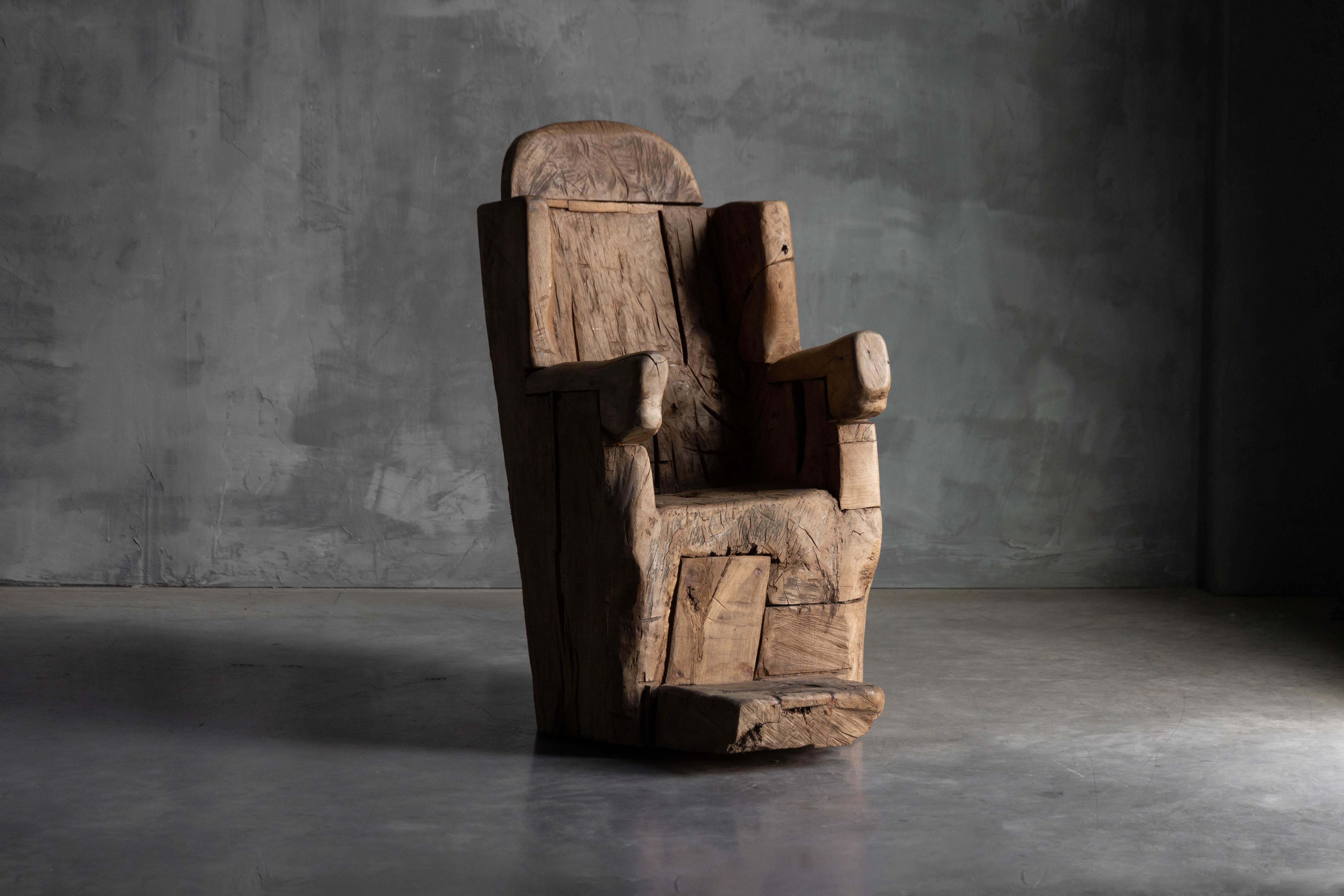 Tallada a partir de un único bloque macizo de madera, esta silla trono monoxilita del siglo XIX encarna un trabajo artesanal ancestral. Su forma escultórica presenta superficies profundamente texturizadas, grietas orgánicas y audaces marcas de