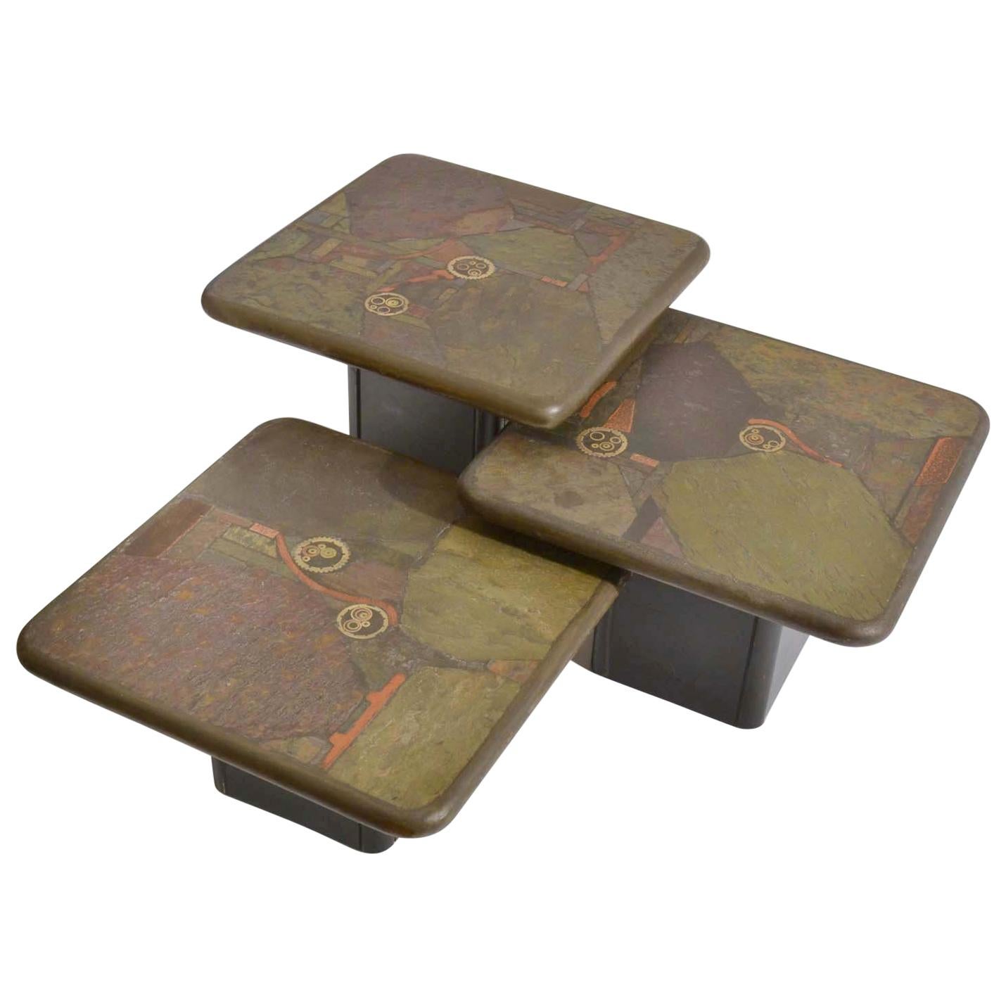 Set of three nesting natural stone mosaic side tables on alternating heights. The tables are inlaid with unpolished textural stone in earth colors and pieces of brass and copper. 
These extraordinary sculptural tables are square 60 x 60 cm tables