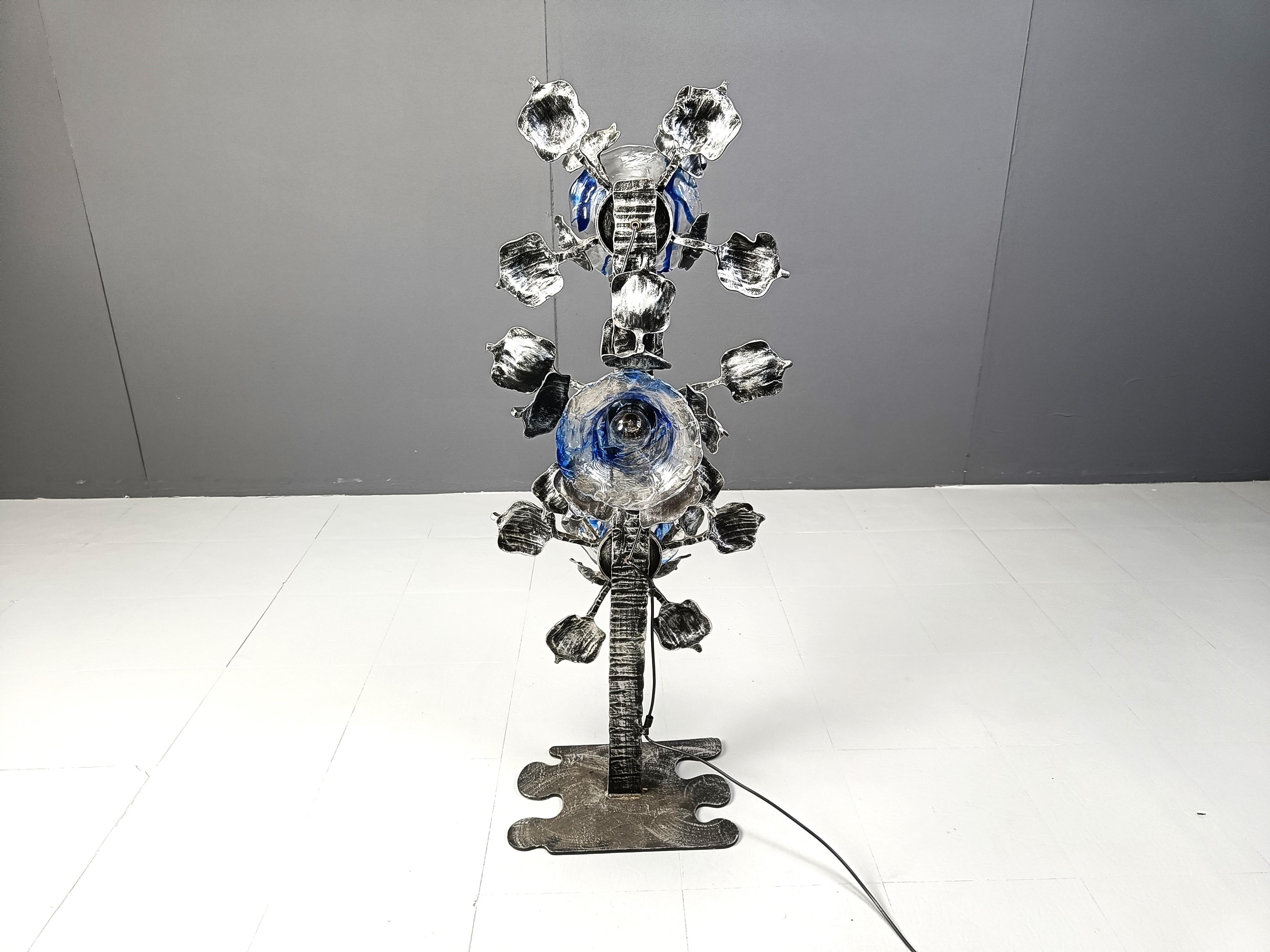 Fantástica lámpara de pie Brutalista fabricada con una base de acero esculpido en forma de flor y pantallas de cristal de murano azul y transparente.

Fantástico diseño brutalista muy decorativo  y emiten una hermosa luz.

años 70 - Italia

Tenemos