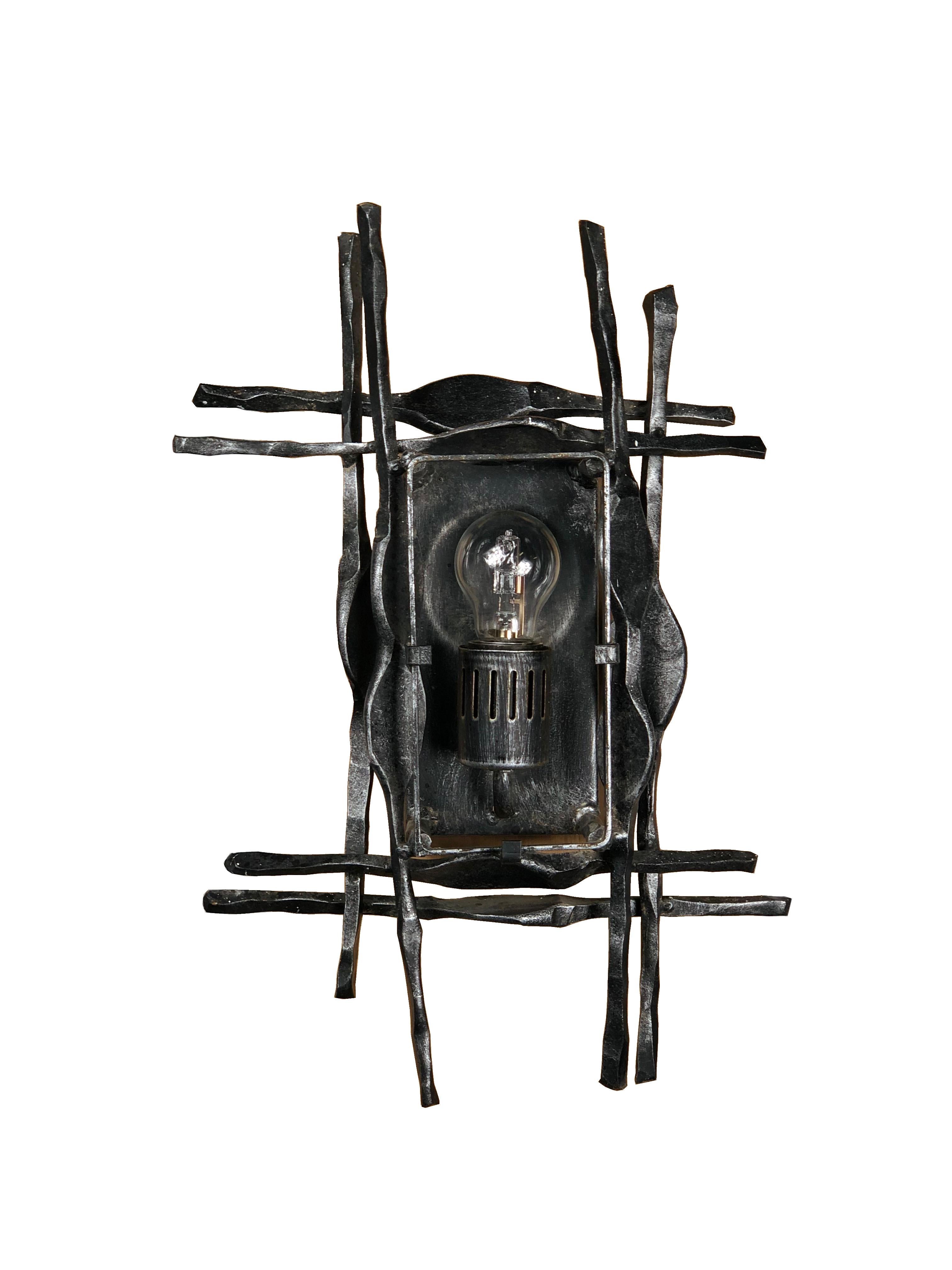 Wall sconce from Swedish design company A & E Design, circa 1970, in the Brutalist style. The hand-wrought iron surround has a good patination and is set off by the Mazzega Murano glass with clear and amber tones. An impressive modernist wall light