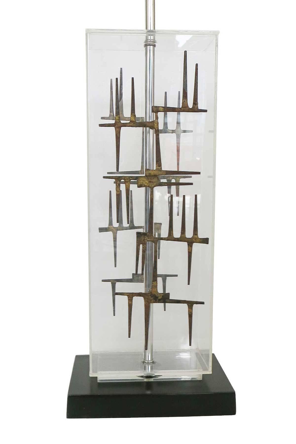 Brutalist nail sculpture Lucite table lamp, circa 1967 made by the Laurel Lamp Co.

This lamp features a hand welded nail sculpture fixed to an acrylic lamp base with a black lacquer base.