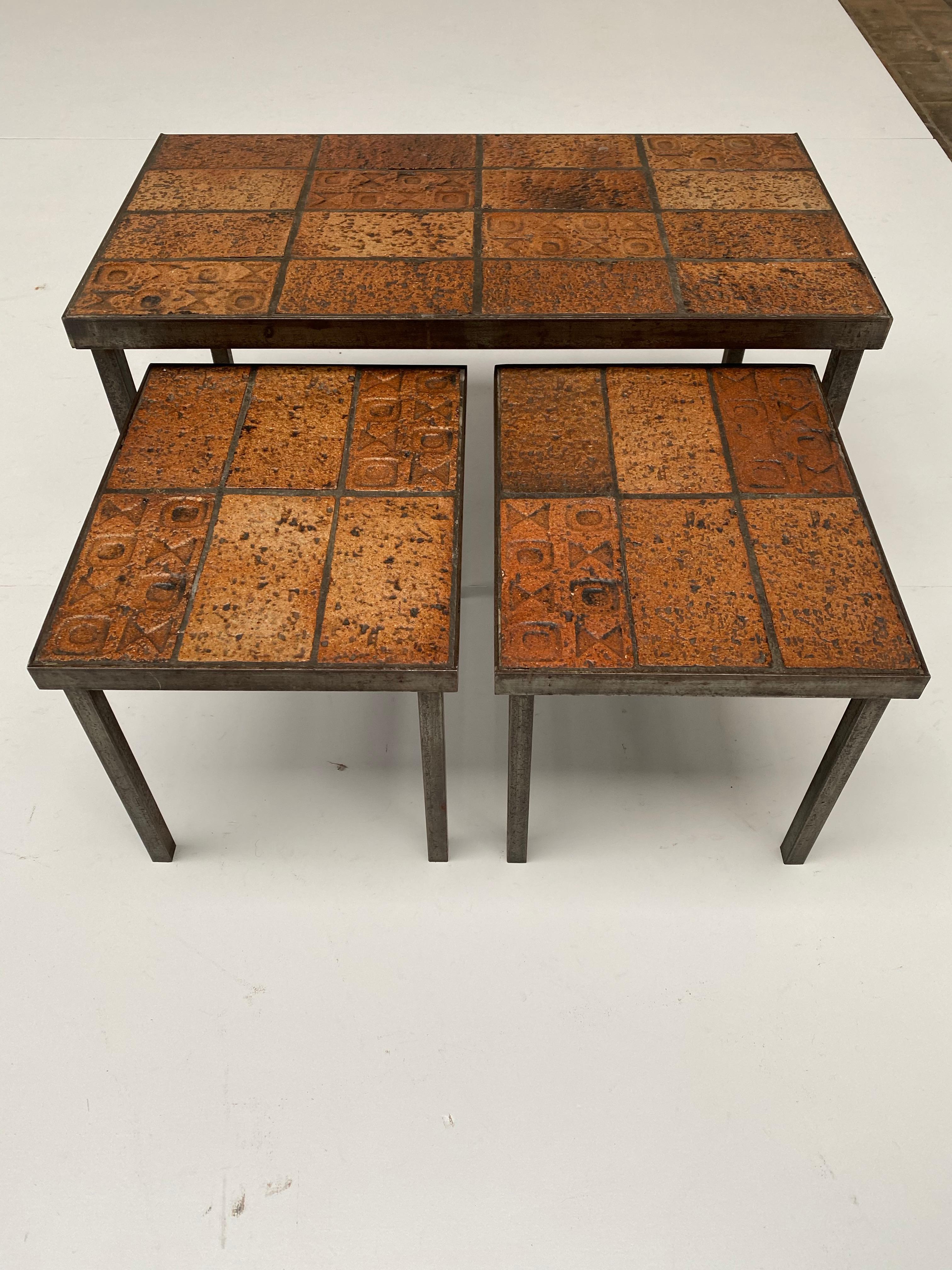 A set of nesting tables in a Brutalist Belgian 1970s style 

The frames are made of solid steel and the tops all have ceramic artwork tiles with geometric symbols imbedded in concrete 

The set is quite heavy and very solid due to the use of all