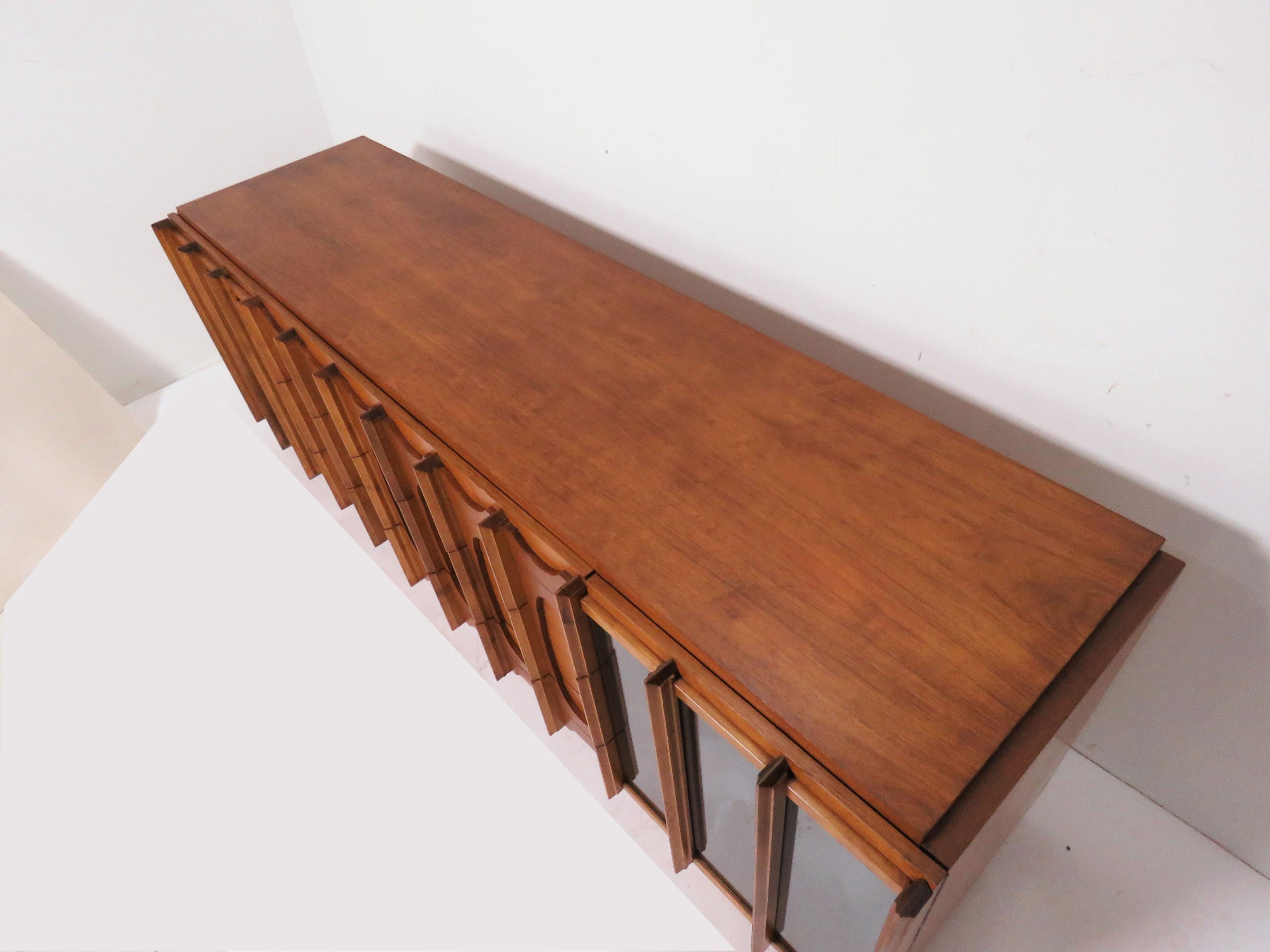 A mid-1960s credenza style dressing cabinet in teak and bleached walnut with smoked mirror door fronts by Tabago Furniture of Montreal, Canada (often incorrectly referred to as “Tobago”). Known for their sculptural designs influenced by the North