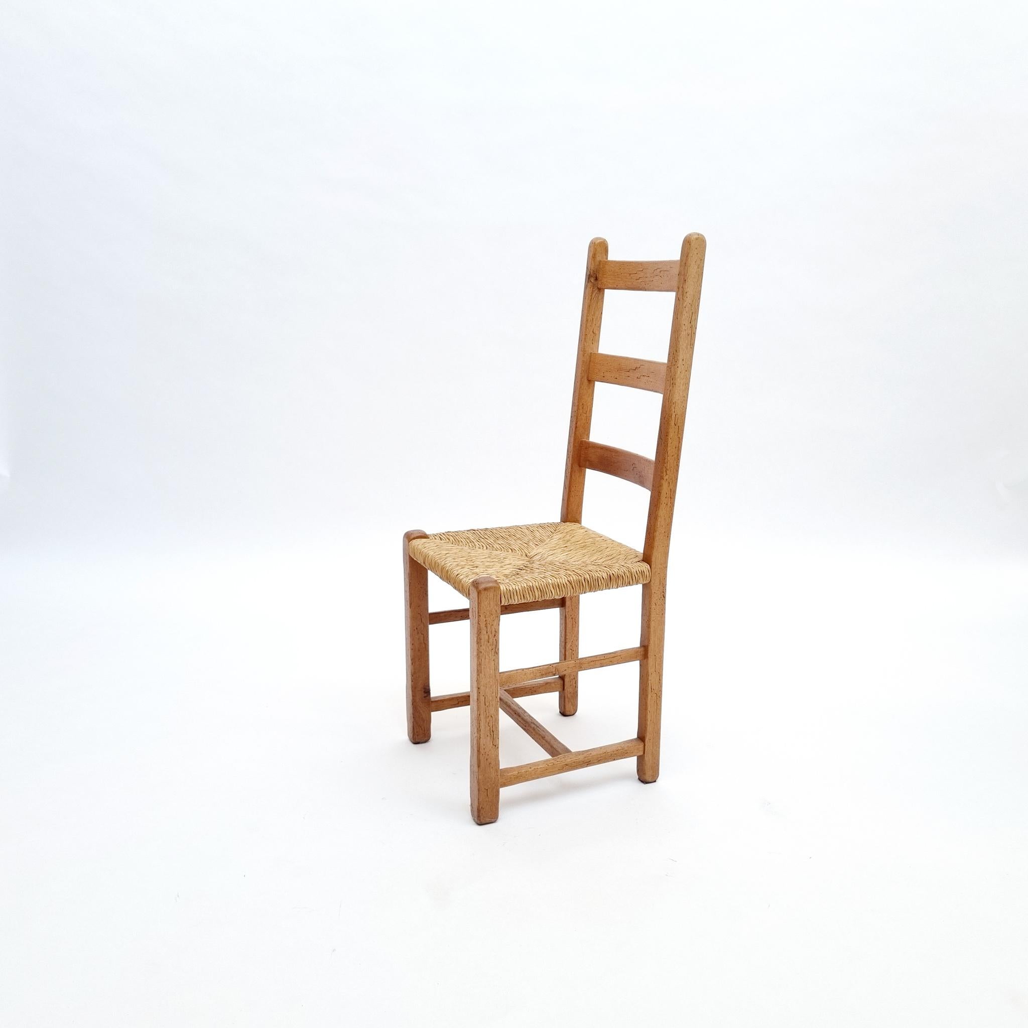 Brutalist oak dining chairs with rush seating, set of six, circa 1870s.