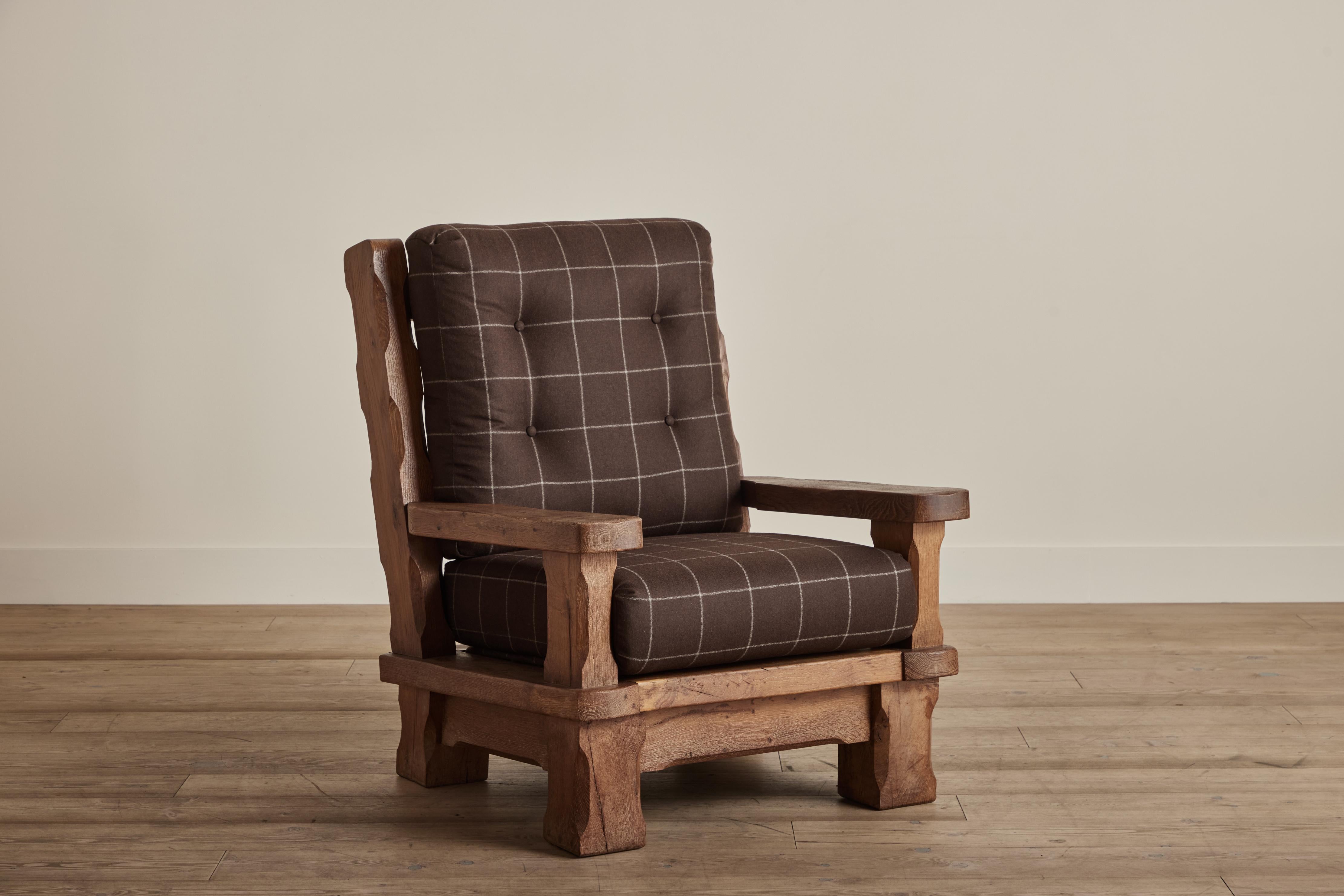 Large Brutalist armchair made of solid oak wood. Chair has new cushion featuring a soft flannel fabric from Holland and Sherry. Some visible wear on wood that is consistent with age and use. 