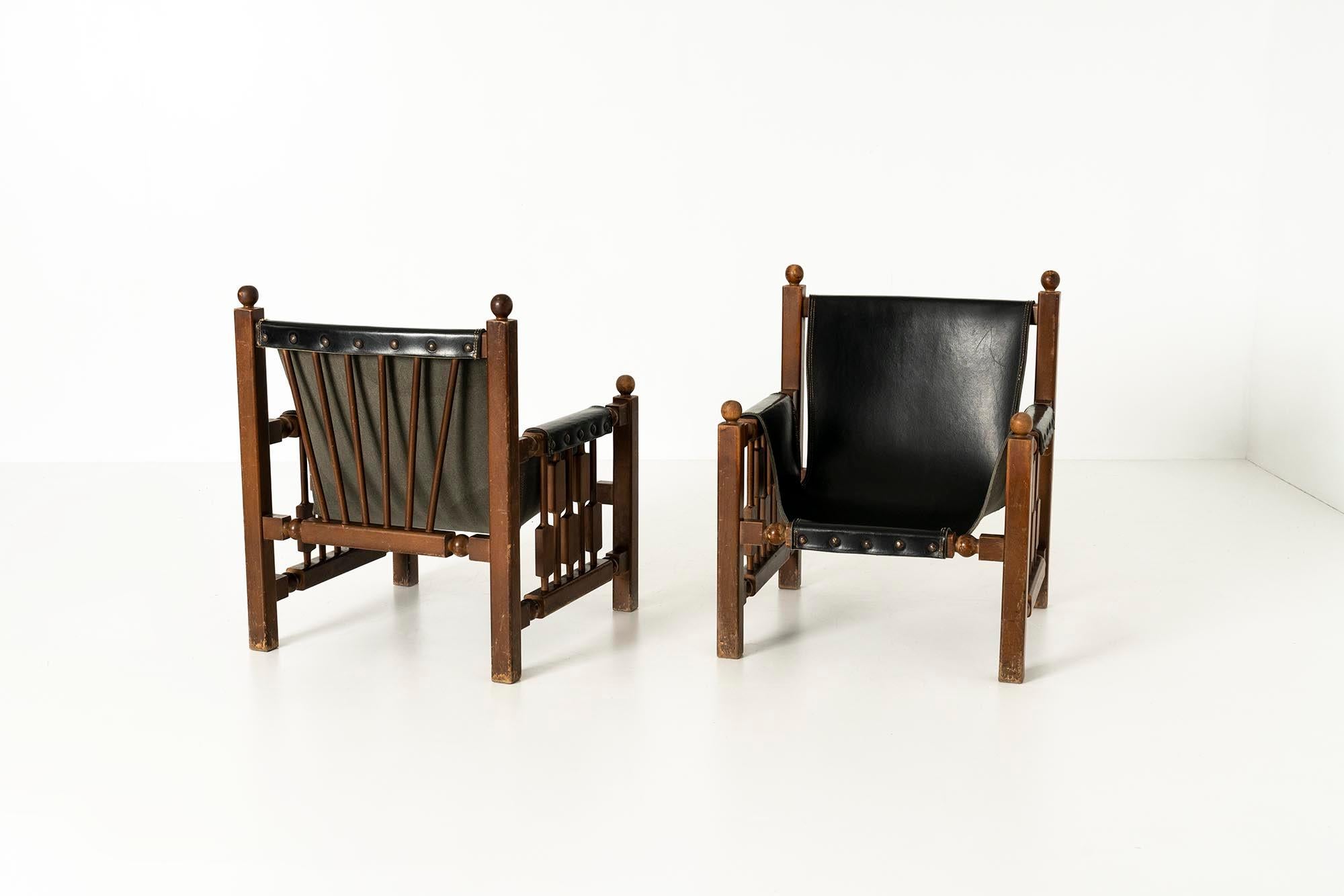 A set of two beautiful rustic brutalist oak chairs in faux leather upholstery in the style of Charles Dudouyt from the 1950s. These lounge chairs carry a strong reminiscence of the style of Charles Dudouyt. The solid oak frame structure is