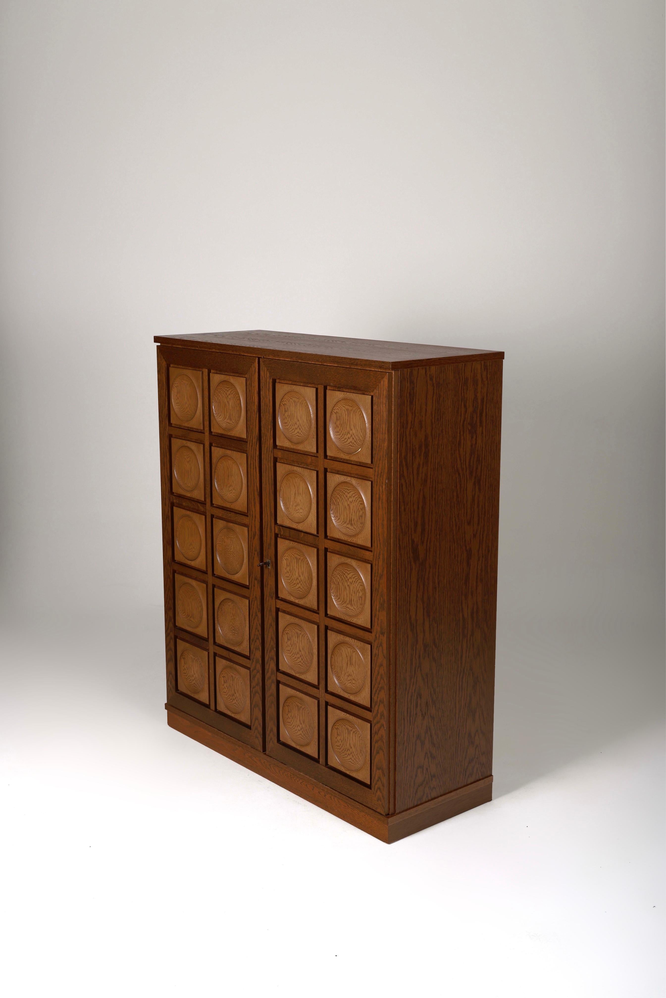 Brutalist chest of drawers by Belgian designer Gerhard Bartels, 1970s. Oak storage unit with two doors featuring circular sculpted motifs and four shelves inside.
LP1103