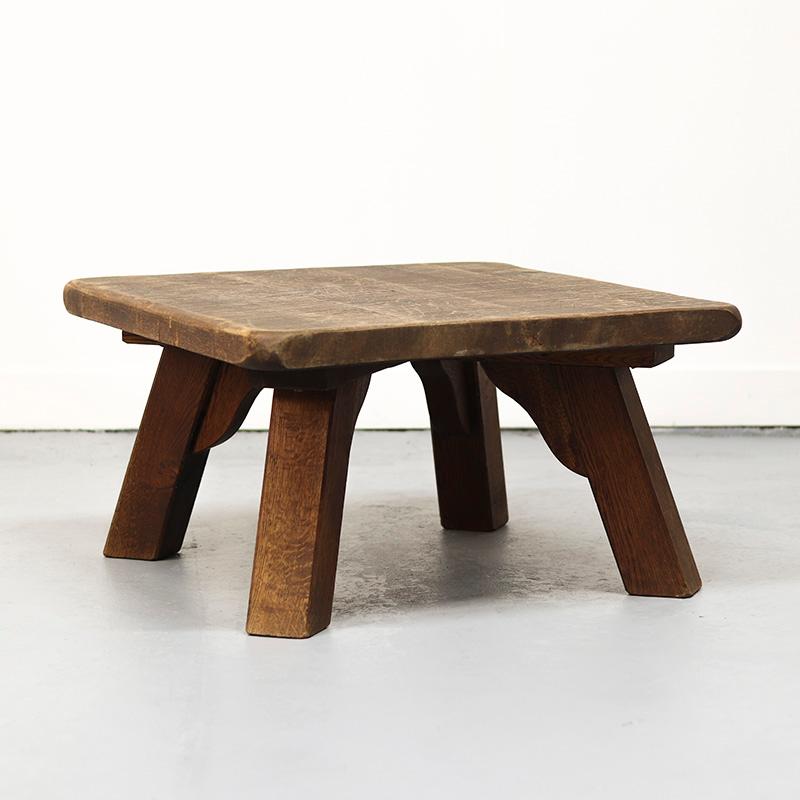 Table basse robuste en chêne brut, avec des pieds épais et un plateau solide et substantiel, illustrant le style brutaliste et l'artisanat. La table présente de légers signes d'utilisation, ce qui renforce son caractère authentique.

Datant des