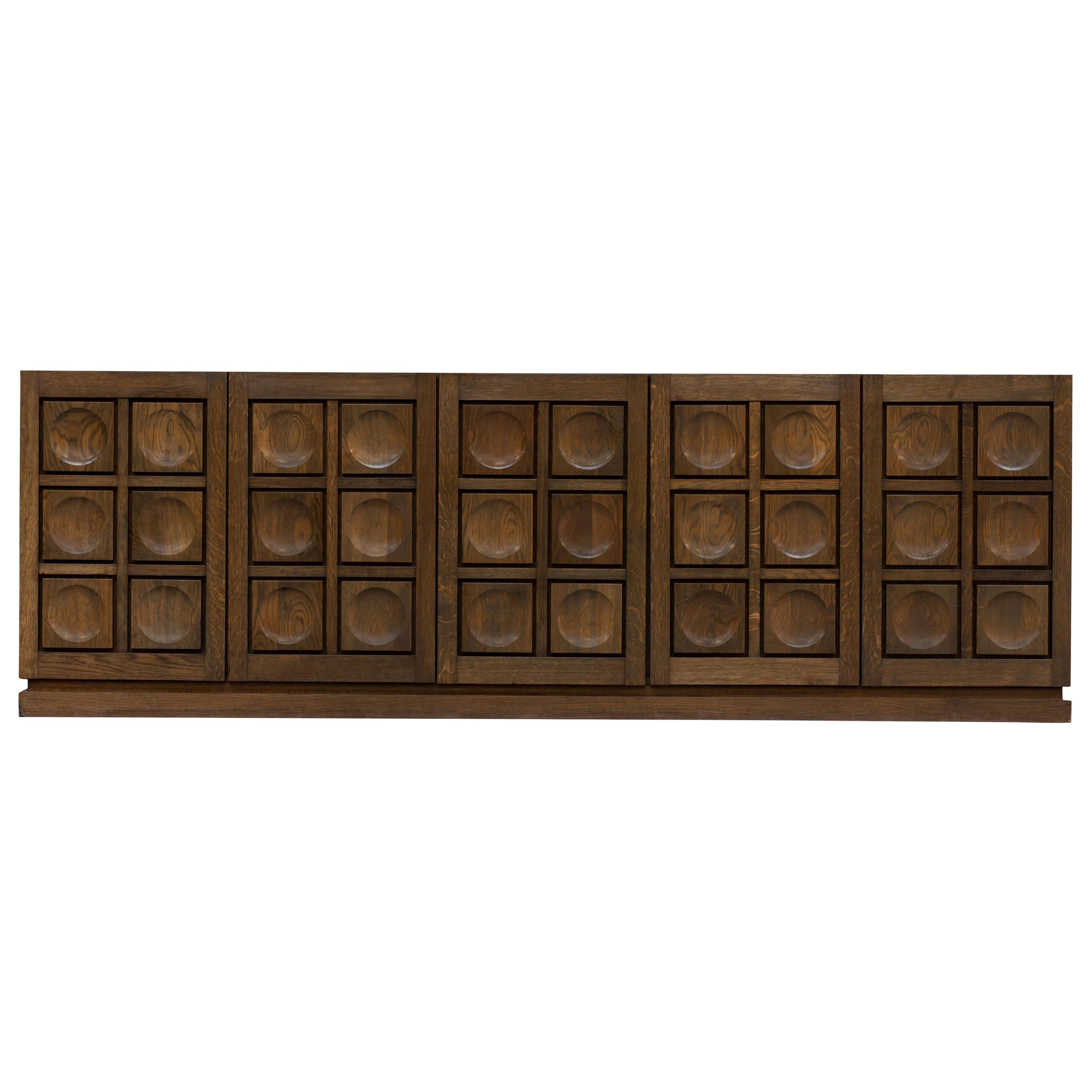 De Coene, brutalist, five-door sideboard, Belgium, 1970s

The geometrical door panels are typical for the era.
The grain of the oak really jumps to the eye.

Would fit well in a Hollywood Regency decor as in a more naturalist