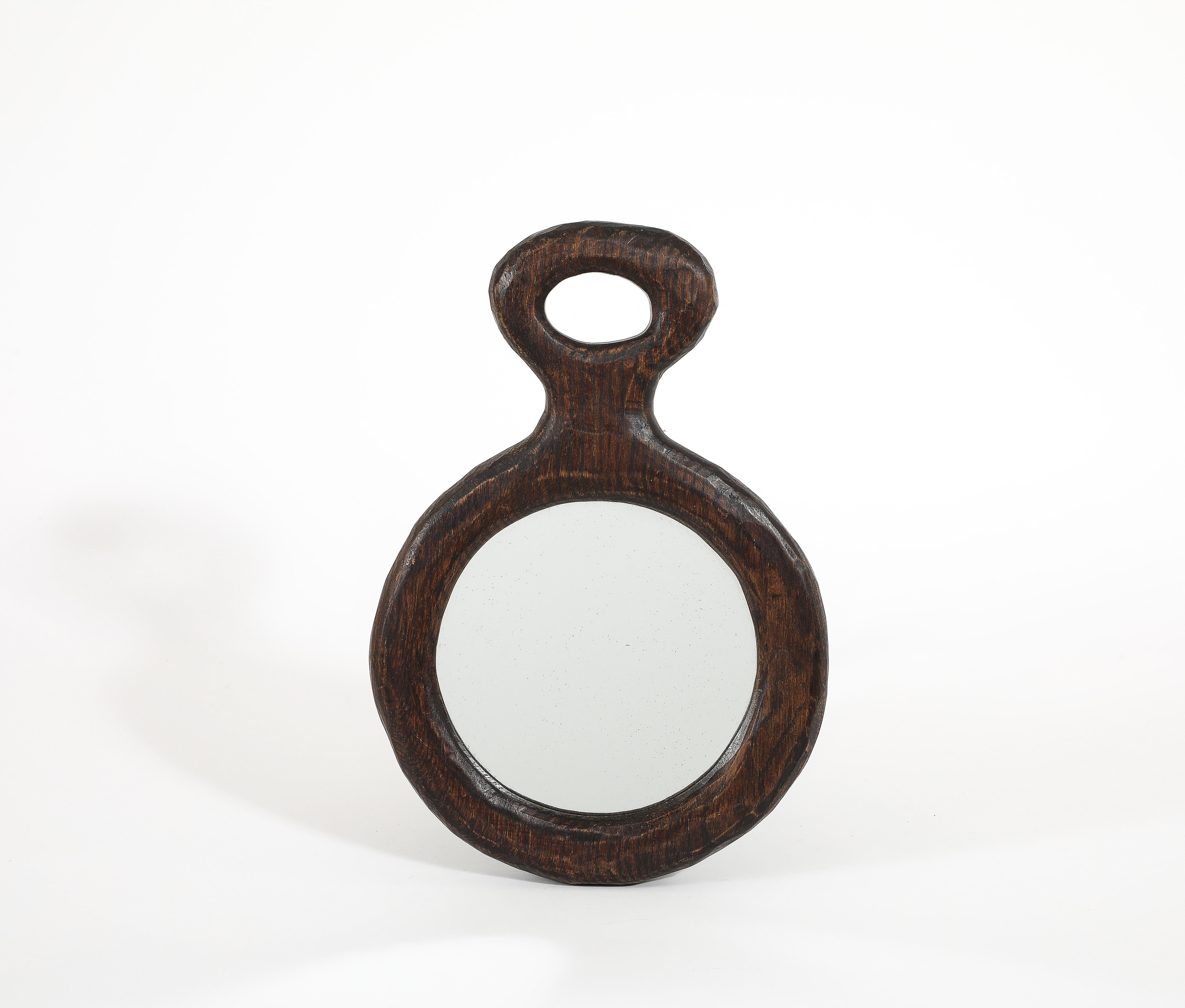 Solid carved mirror with a stylized handle.
