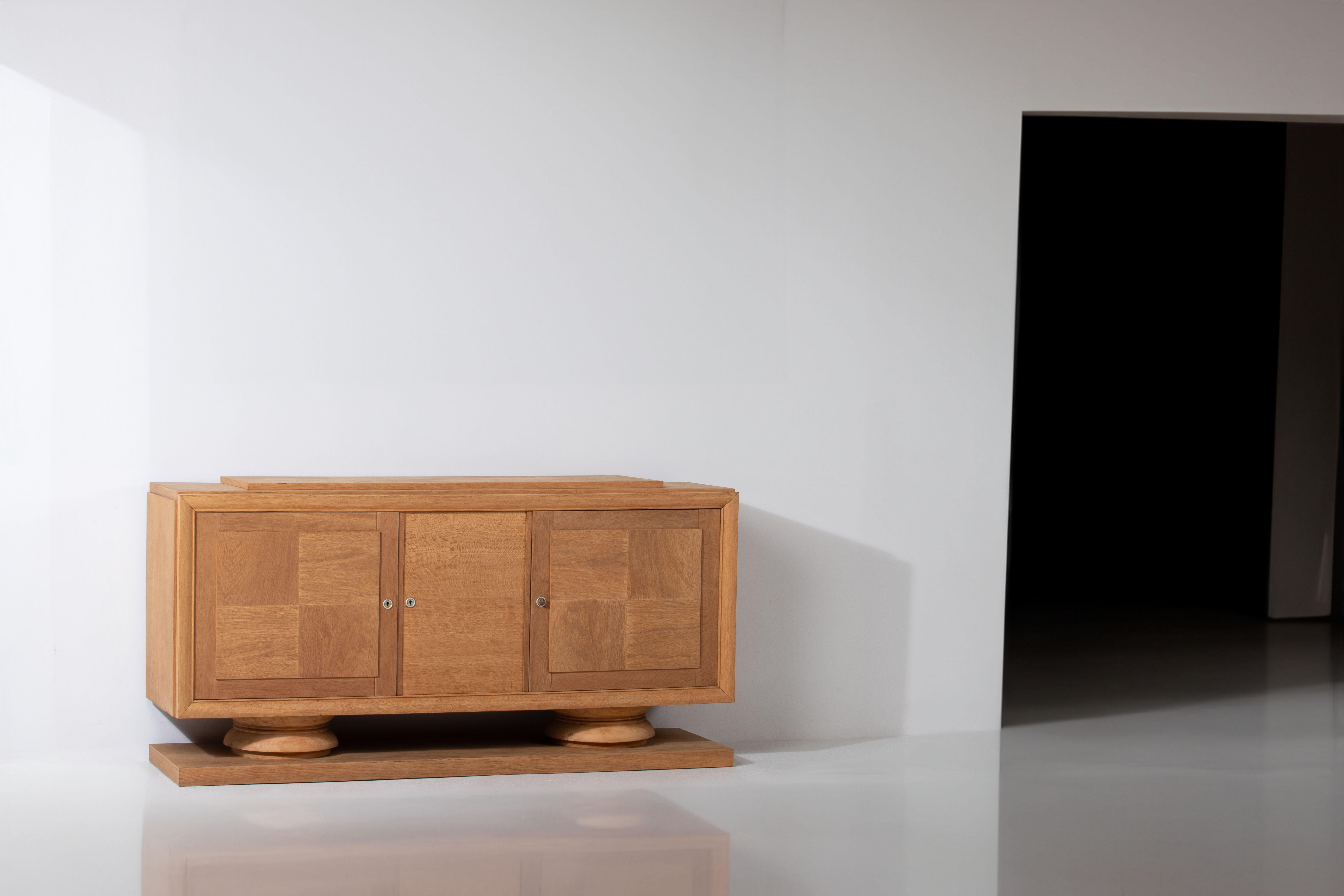 Introducing a sculptural French buffet from the 1940s, crafted with the utmost elegance and sophistication. This remarkable piece features clean lines and minimalistic doors adorned with a charming checked pattern, adding a touch of visual