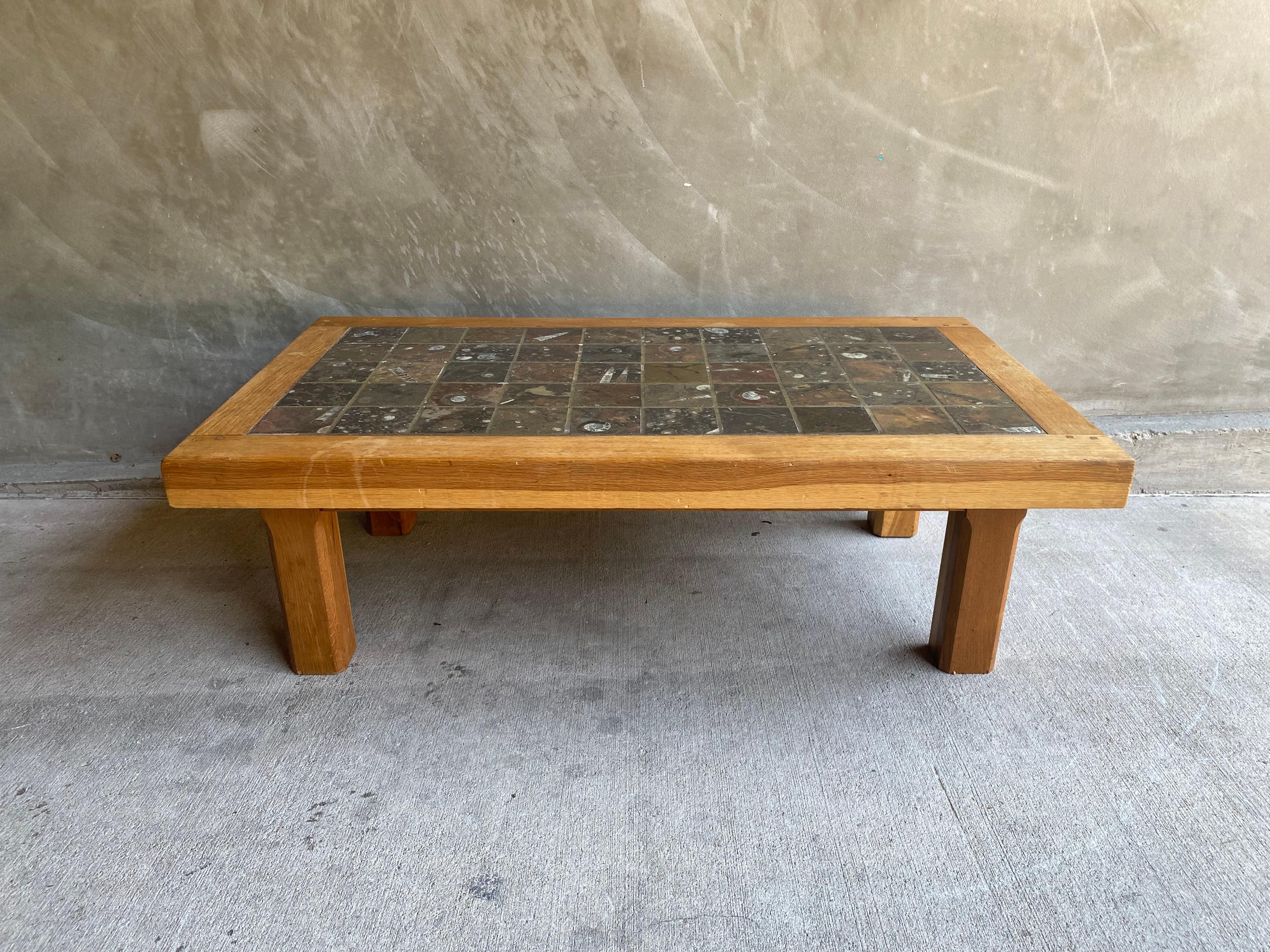Solid oak framed cocktail table with exposed joinery and inlaid fossilized marble/stone top. Brutalist style. Stone color range includes charcoal, black, gray, olive green, rust, brown and white. Belgium, 1960's.