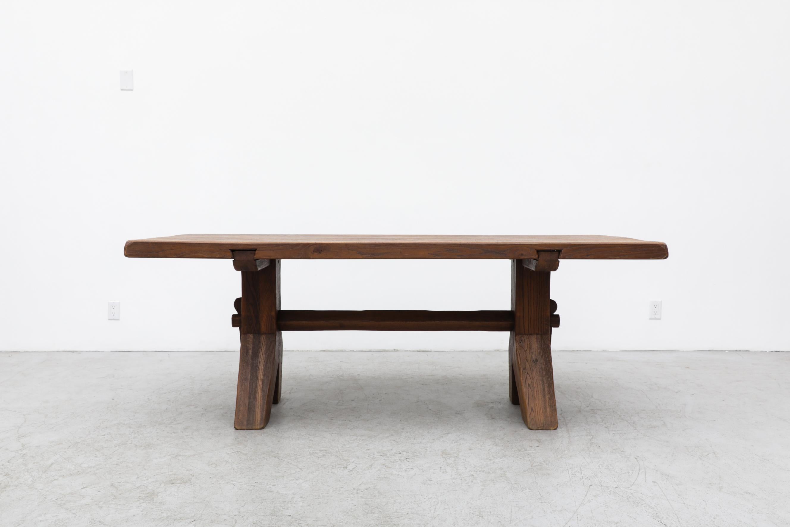 DePuydt dining table, shown with a matching set of 8 dining chairs. Heavy dark oak table with coarse grain and Brutalist feel. Peg tension fastening of the cross support to the base. In original condition with visible wear consistent with its age