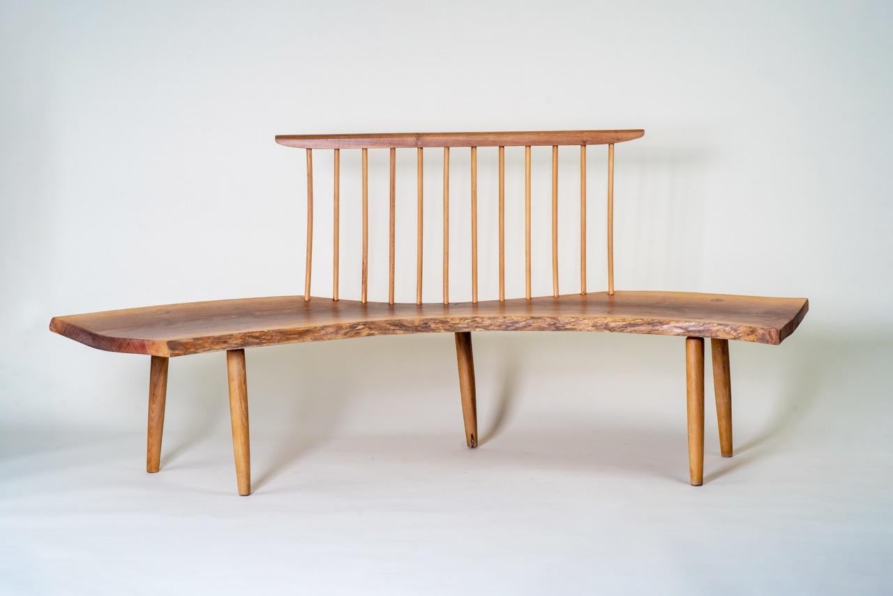 Vintage live-edge bench crafted from solid oak wood, showcasing a beautifully sculptural seat with organic, flowing contours that emphasise the natural character of the material. The spindle backrest and elegantly tapered legs enhance its refined
